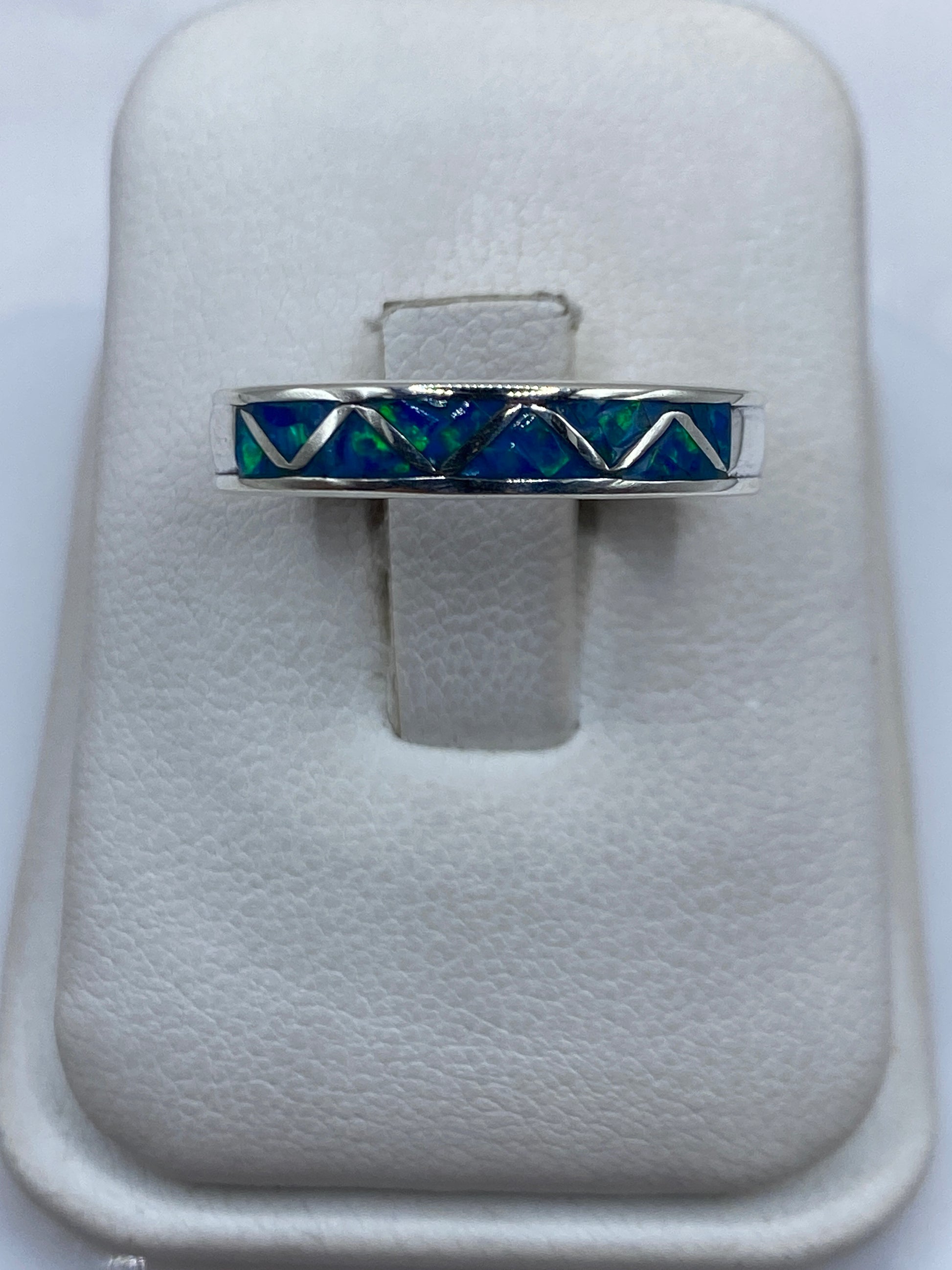 Anillo de plata .950 con ópalo de fuego azul en diseño geométrico sobre cojín de terciopelo