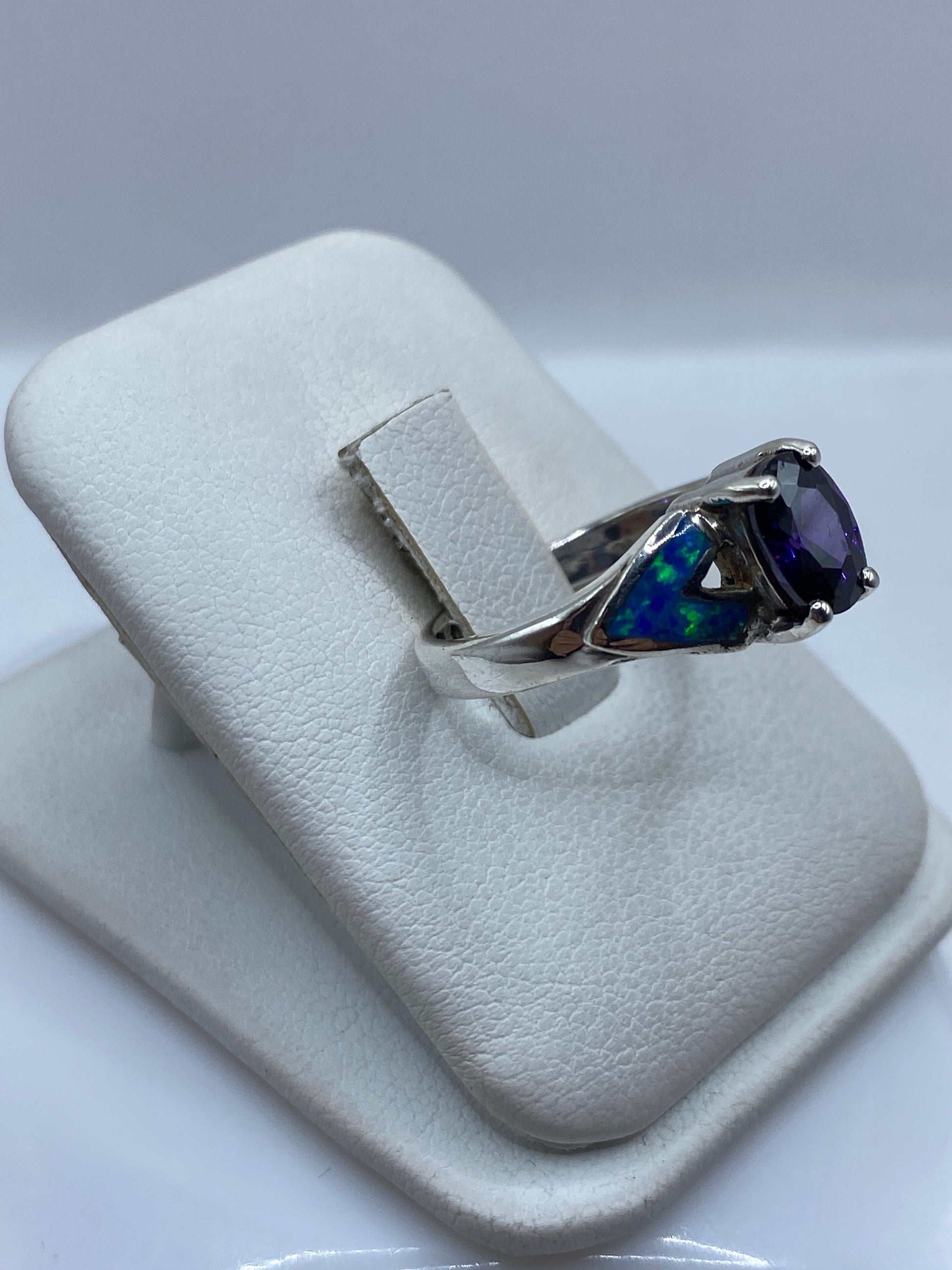 Vista lateral del anillo mostrando el engaste a mano y el juego de colores azul y verde del ópalo