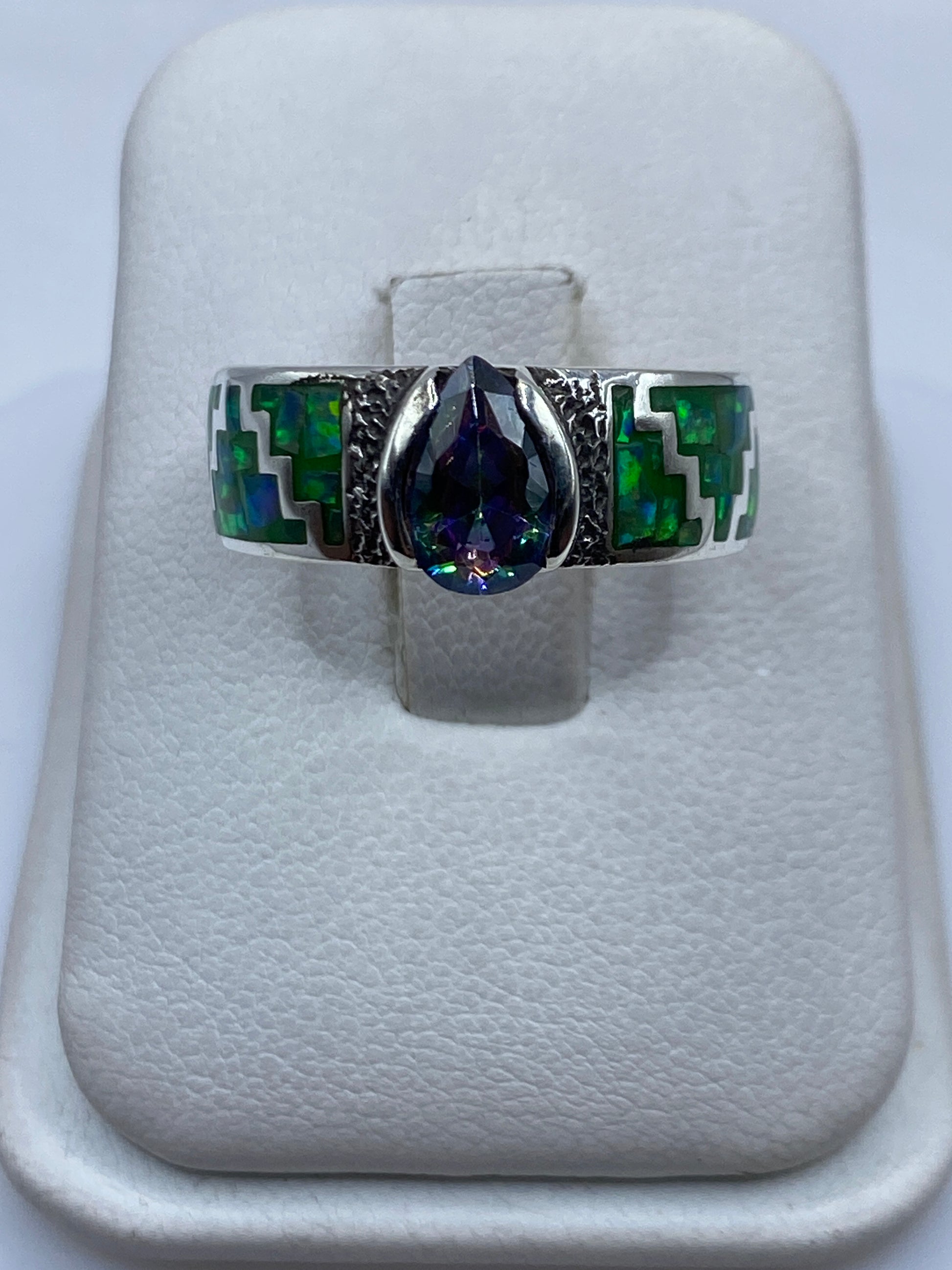 Anillo de plata .950 con ópalo de fuego verde limón y motivos prehispánicos en la mano de una persona