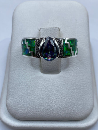 Anillo de plata .950 con ópalo de fuego verde limón y motivos prehispánicos en la mano de una persona