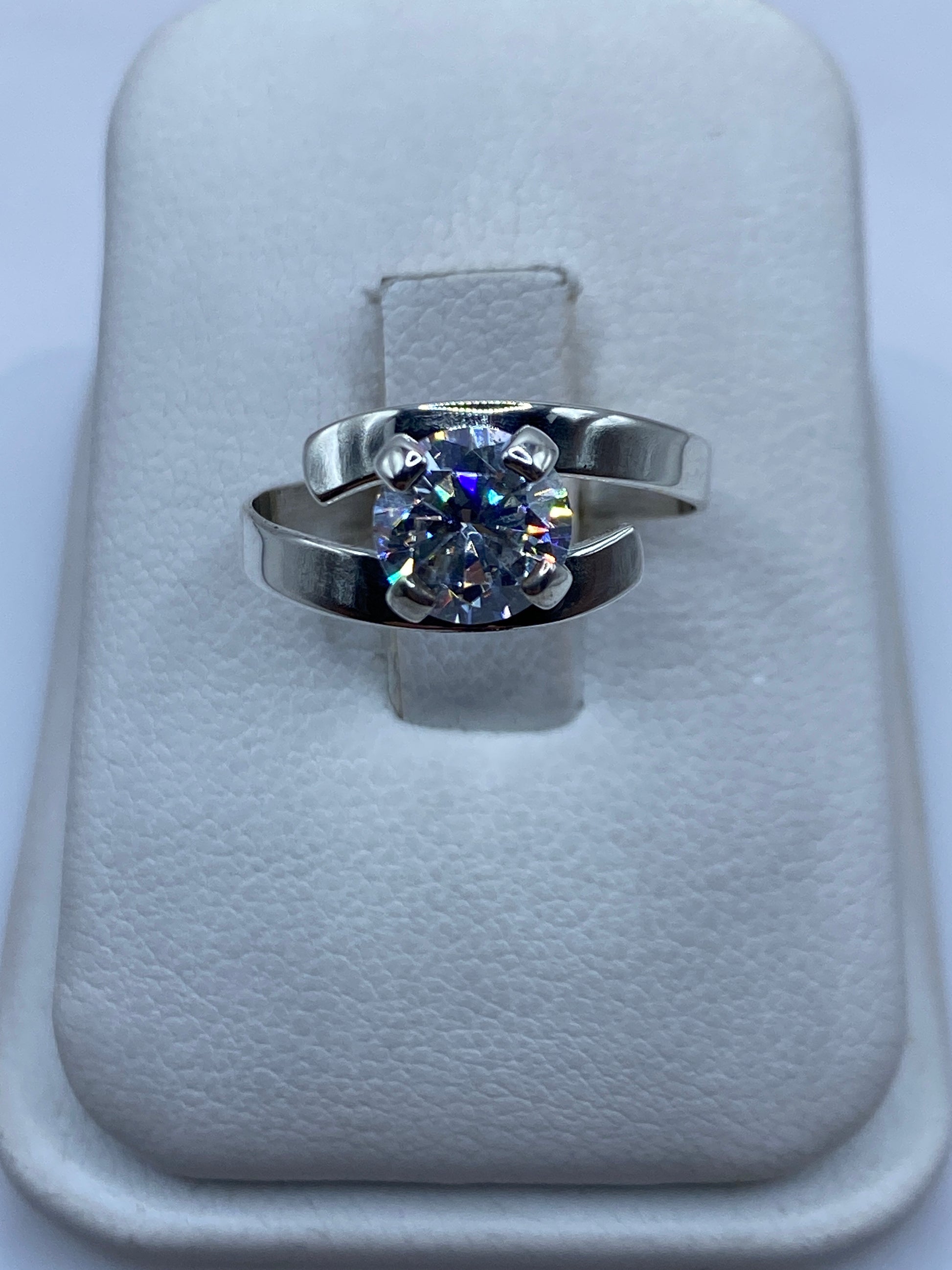 Anillo de plata solitario con circonia blanca brillante, vista frontal sobre almohada de terciopelo