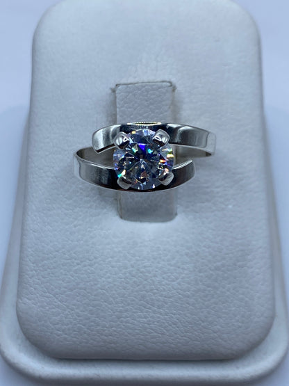Anillo de plata solitario con circonia blanca brillante, vista frontal sobre almohada de terciopelo
