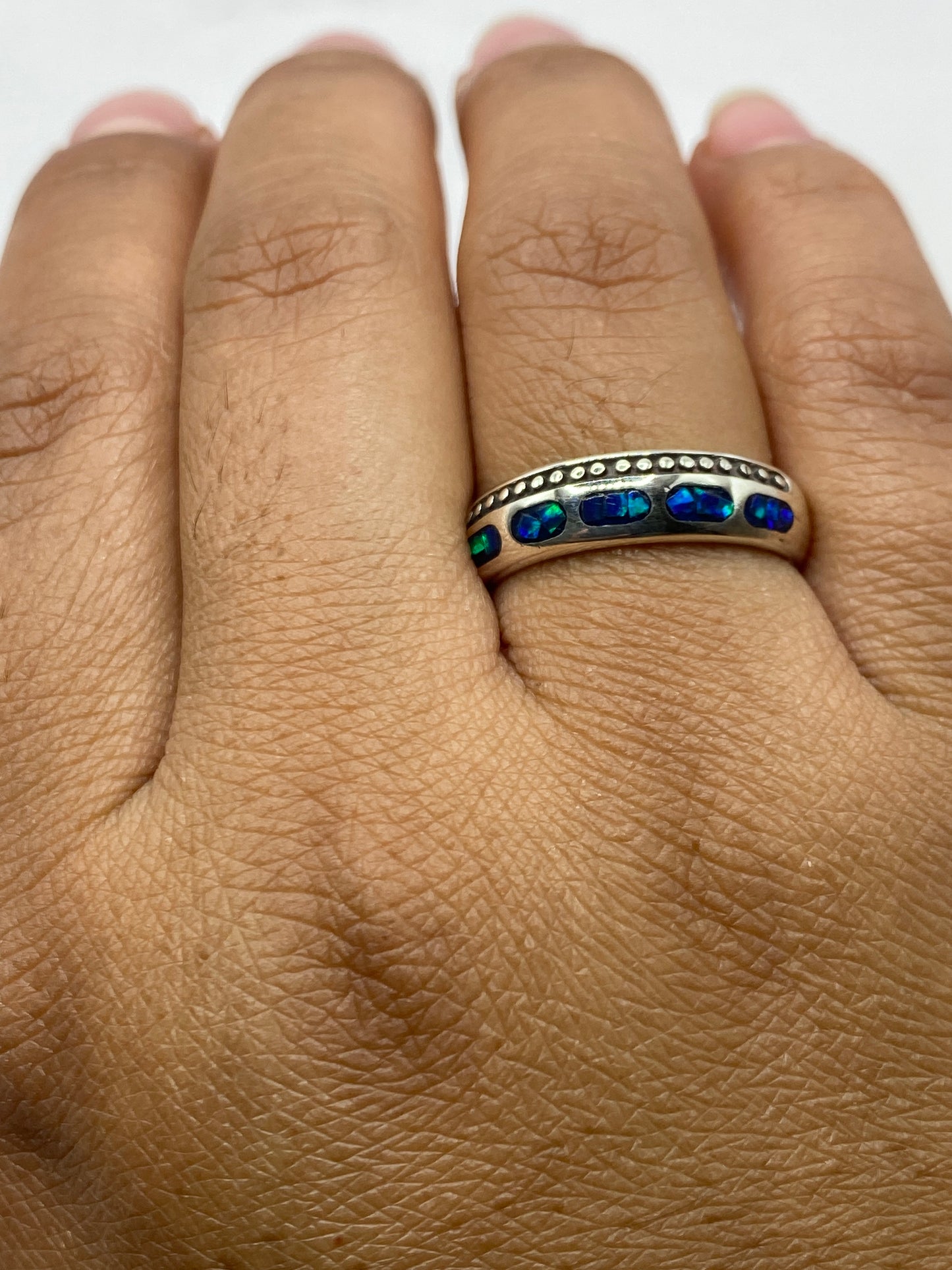 Anillo en la mano mostrando el juego de luz único del ópalo de fuego azul