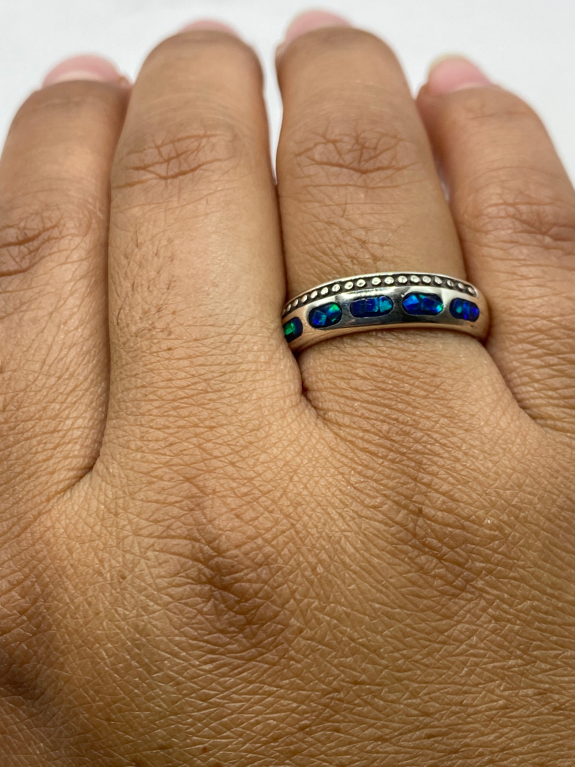 Anillo en la mano mostrando el juego de luz único del ópalo de fuego azul