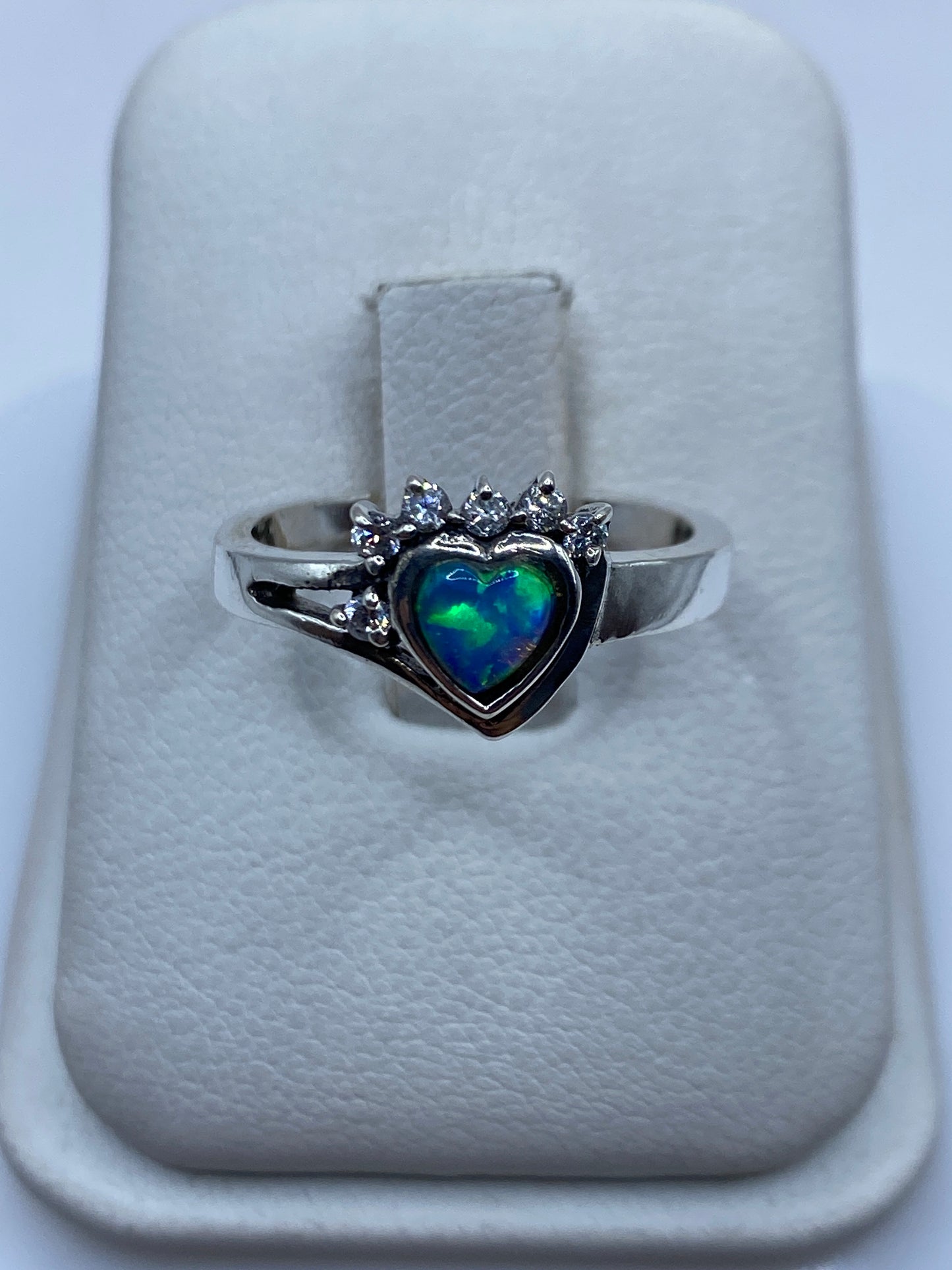 Anillo de plata con ópalo de fuego azul cielo y corona de circonias blancas, visto de frente en estuche blanco
