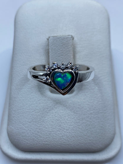 Anillo de plata con ópalo de fuego azul cielo y corona de circonias blancas, visto de frente en estuche blanco