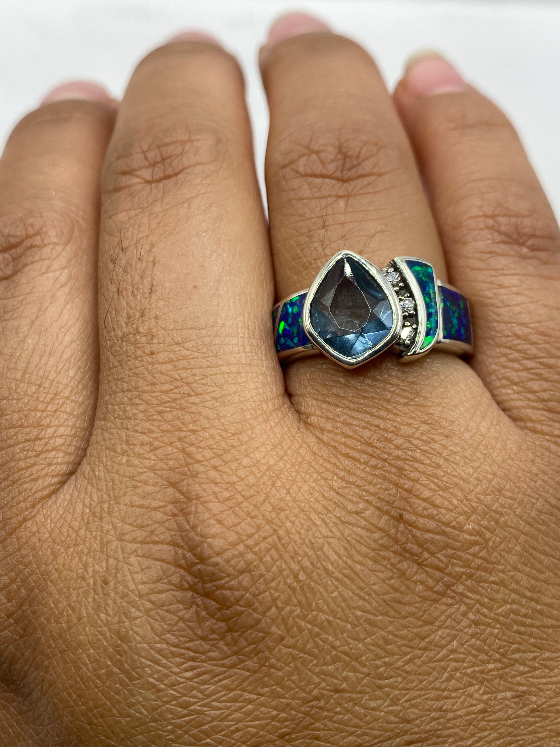 Anillo de ópalo azul en dedo mostrando brillo y fuego natural de la piedra
