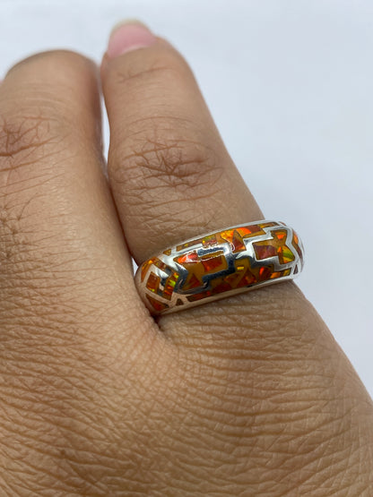 Ópalo de fuego en anillo de plata sobre fondo gris mostrando brillo natural