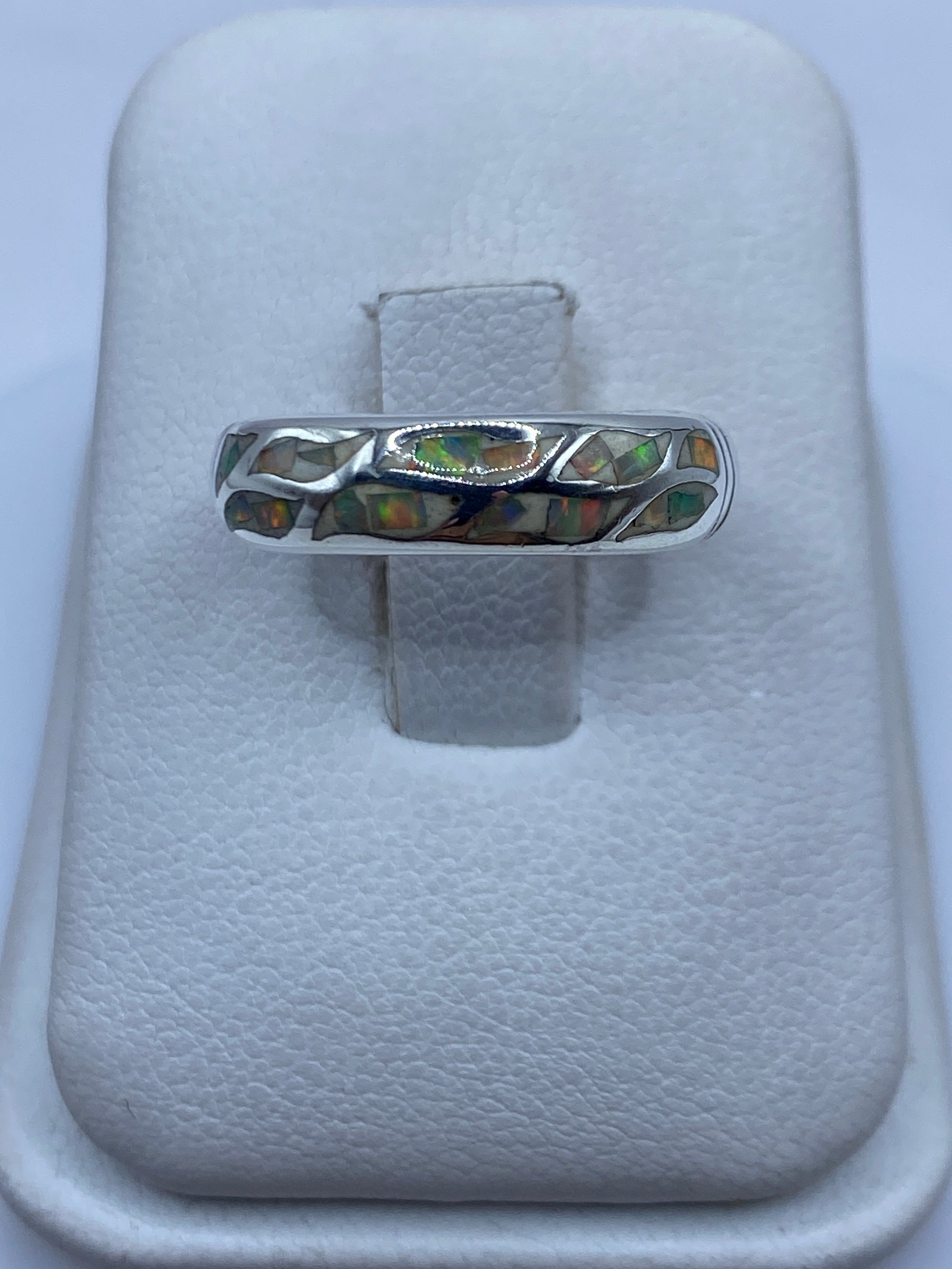 Anillo de plata con ópalo de fuego multicolor, mostrando el juego de colores naranjas y verdes