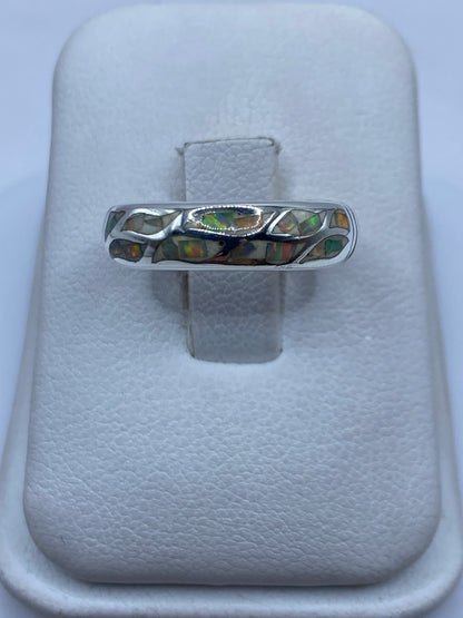 Anillo de plata con ópalo de fuego multicolor, mostrando el juego de colores naranjas y verdes