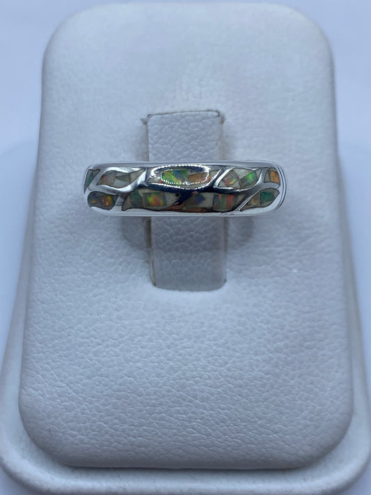 Anillo de plata con ópalo de fuego multicolor, mostrando el juego de colores naranjas y verdes