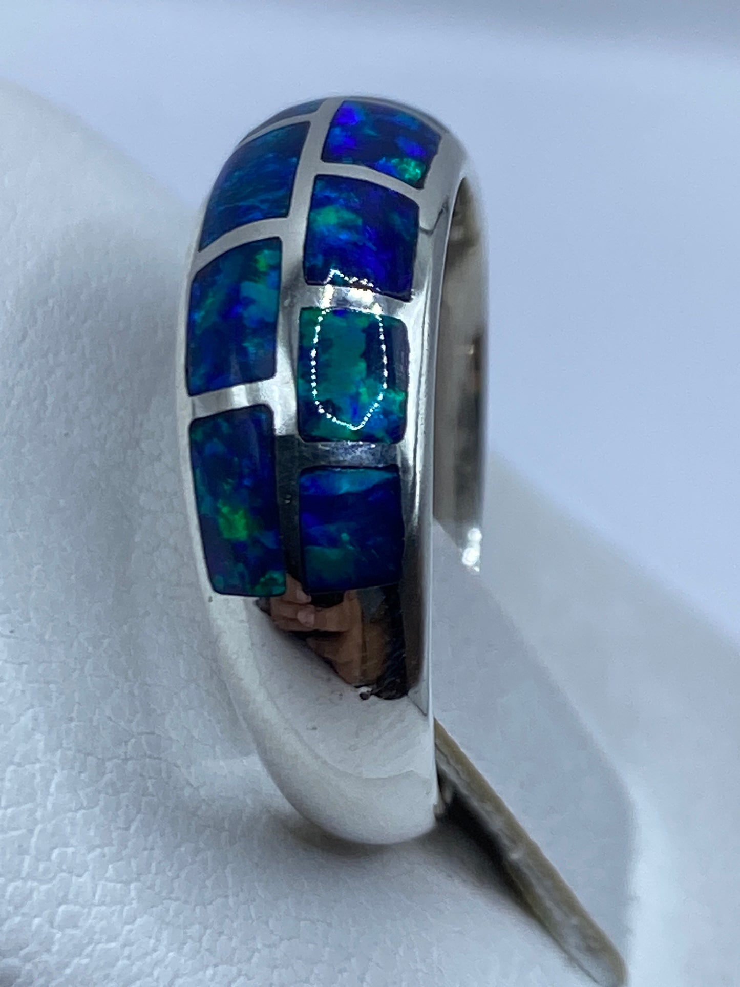 Anillo de plata moderno con ópalo en la mano, vista lateral con diseño minimalista