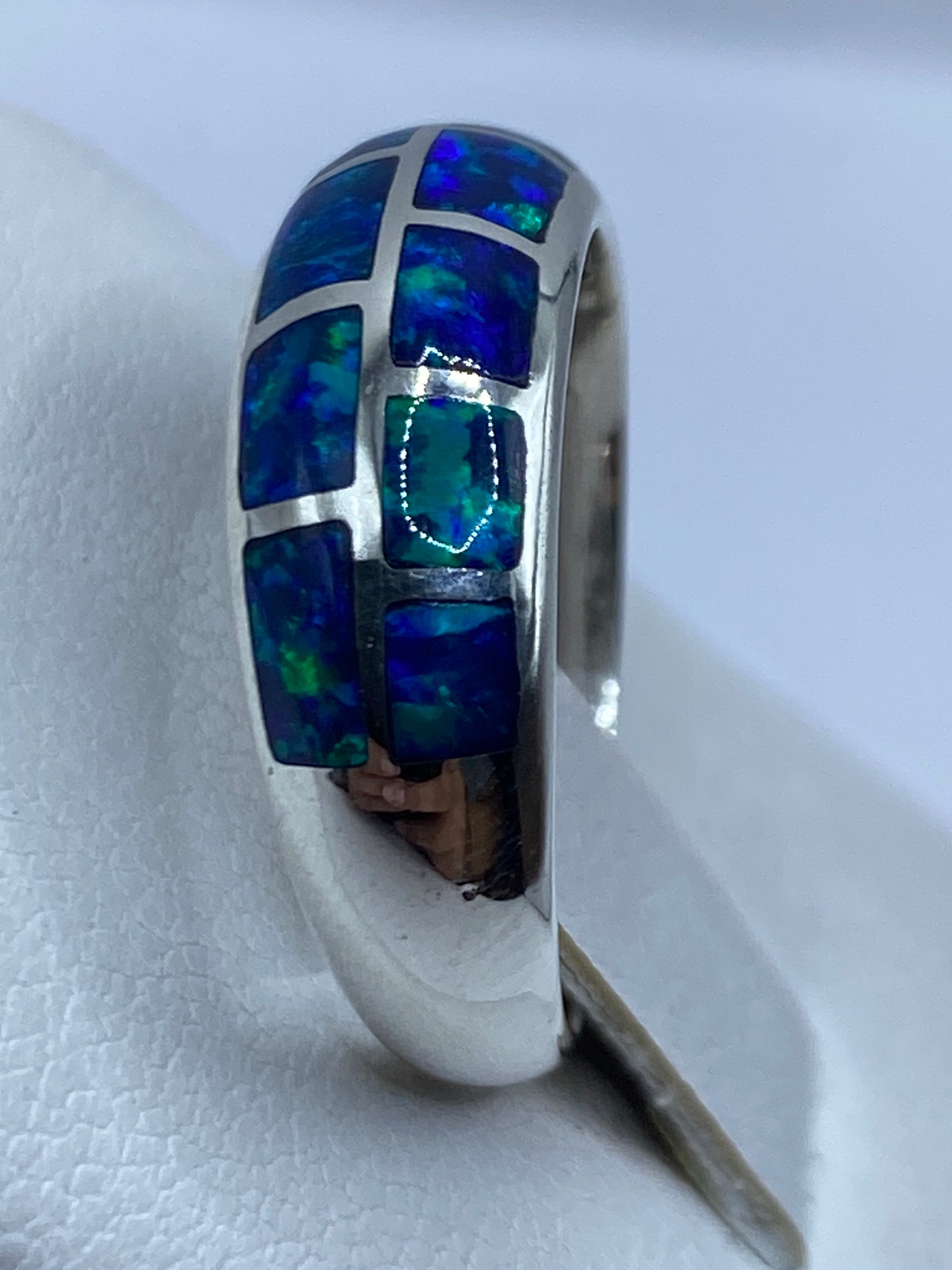 Anillo de plata moderno con ópalo en la mano, vista lateral con diseño minimalista