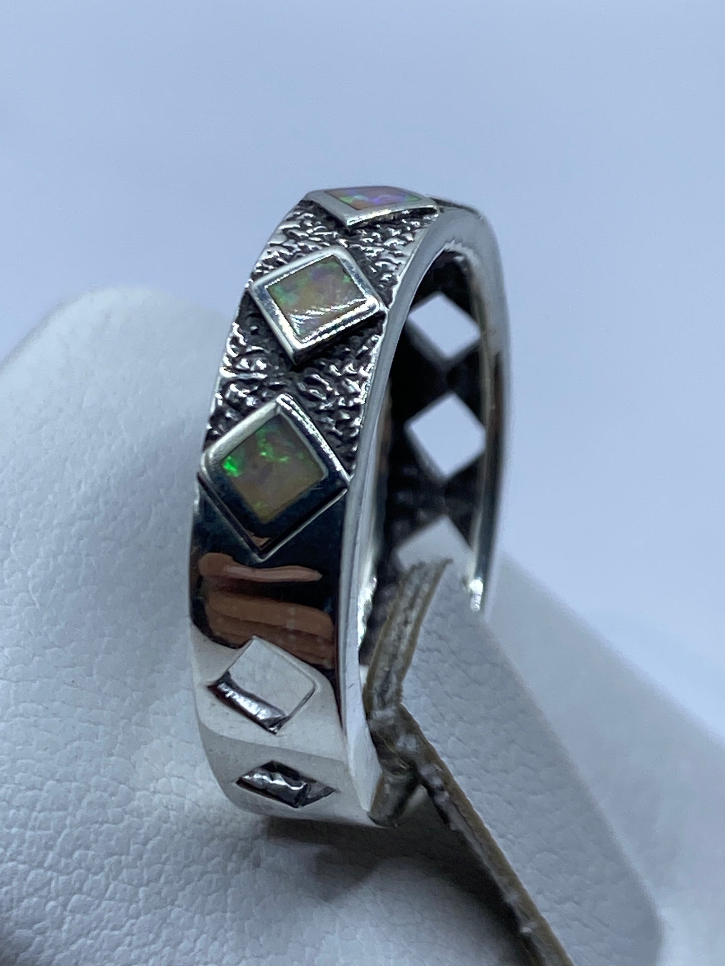 Anillo unisex con textura martillada y ópalo multicolor puesto en mano