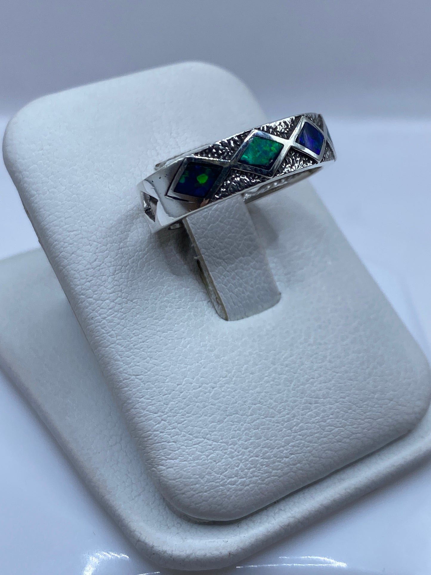Detalle lateral del anillo unisex mostrando el engaste y el juego de color del ópalo