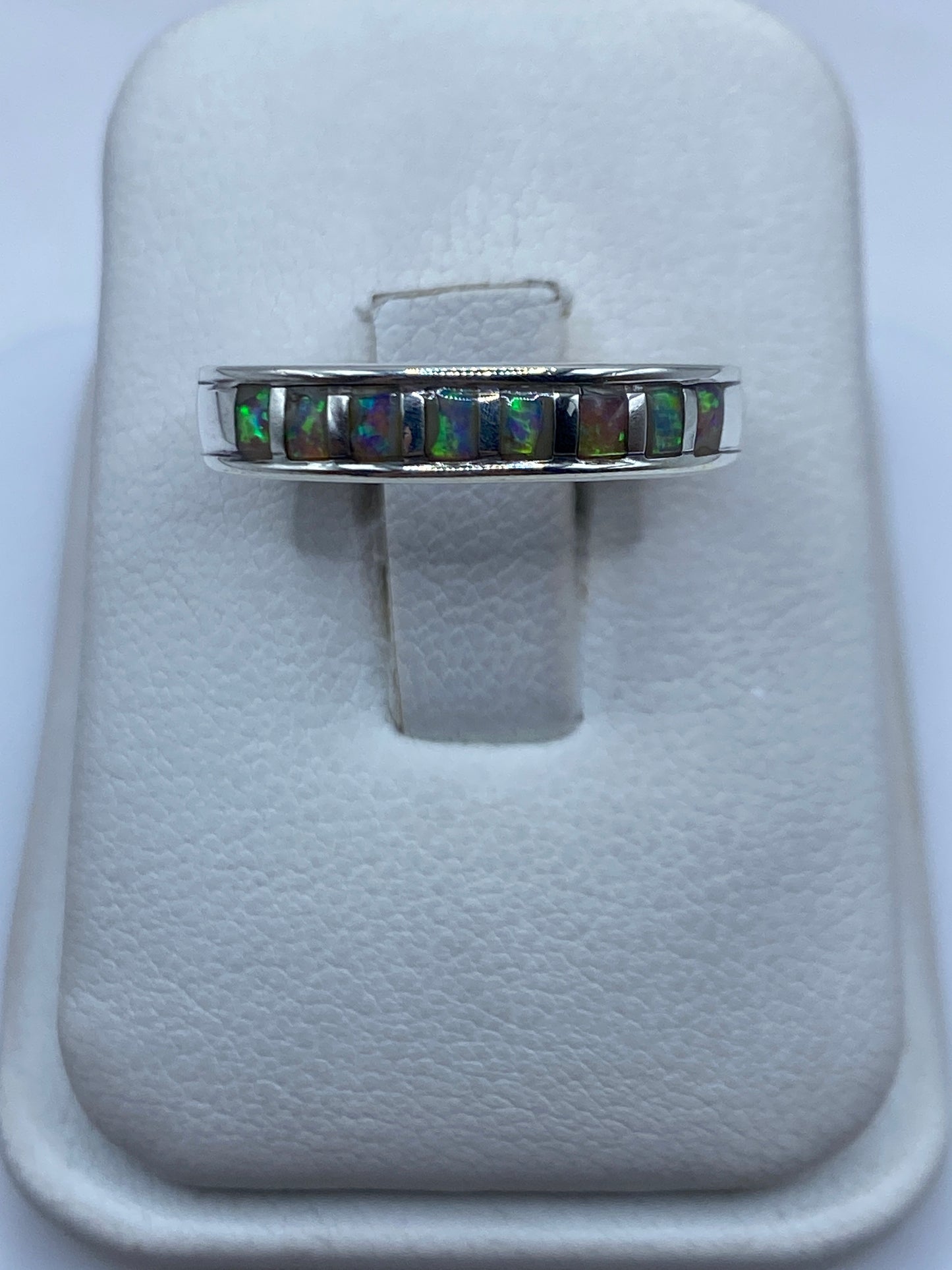 Anillo de plata con ópalo de fuego multicolor mostrando juego de luz verde y naranja