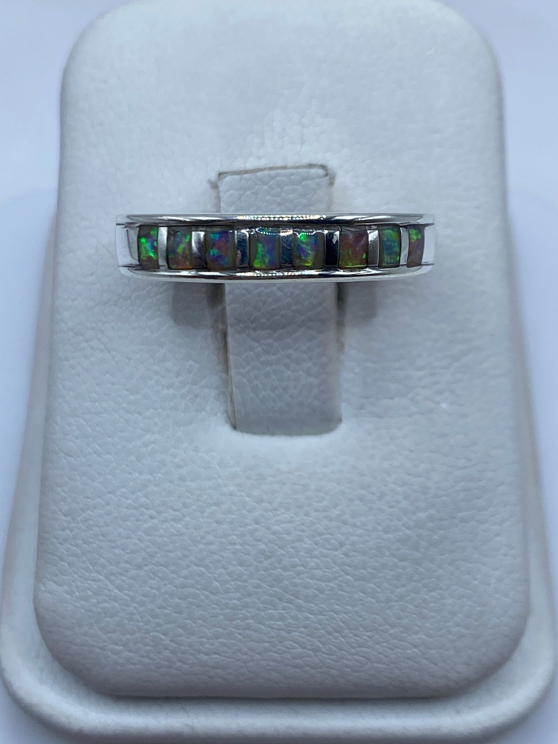 Anillo de plata con ópalo de fuego multicolor mostrando juego de luz verde y naranja