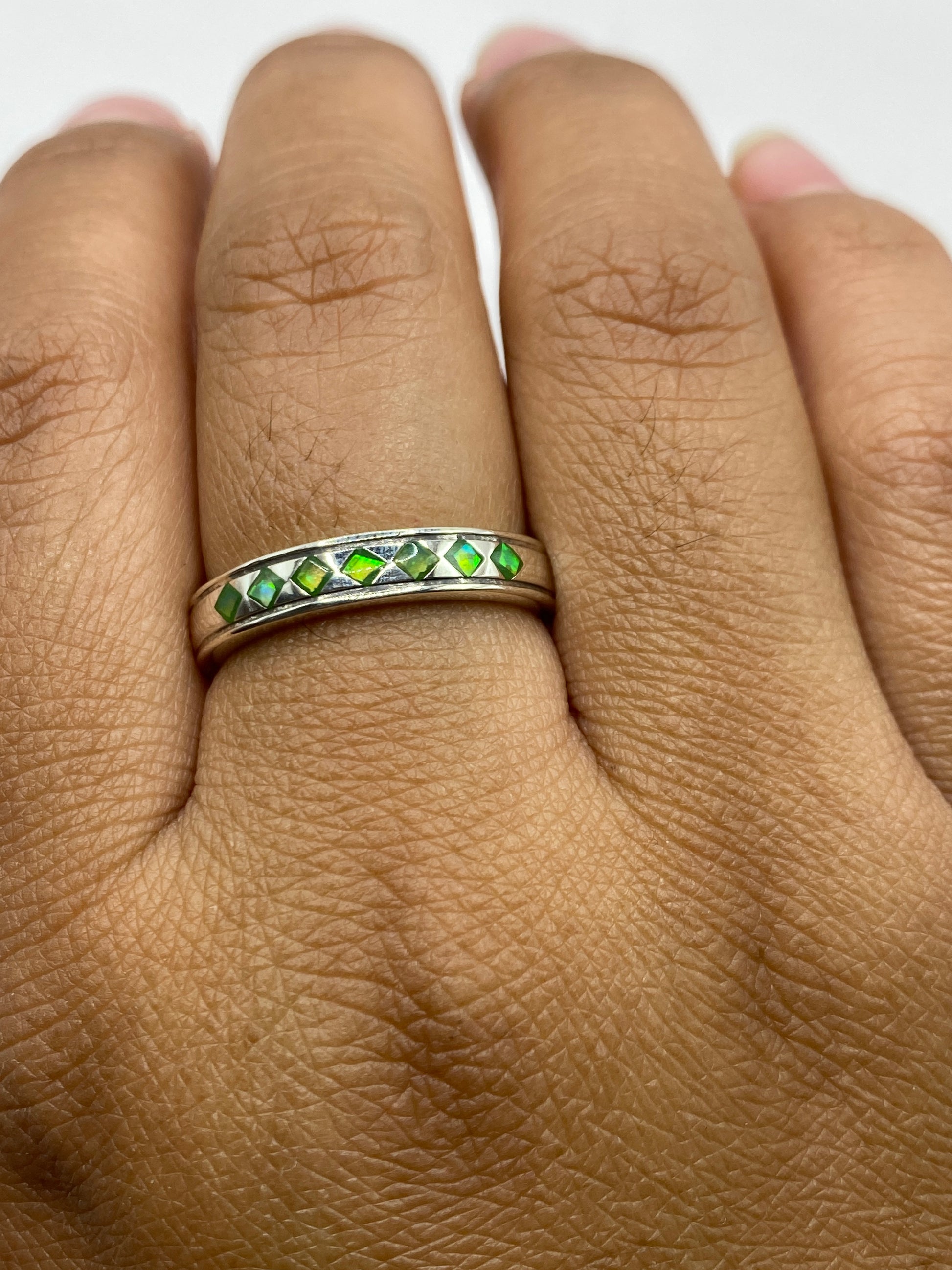 Anillo en mano mostrando los reflejos verdes del ópalo de fuego
