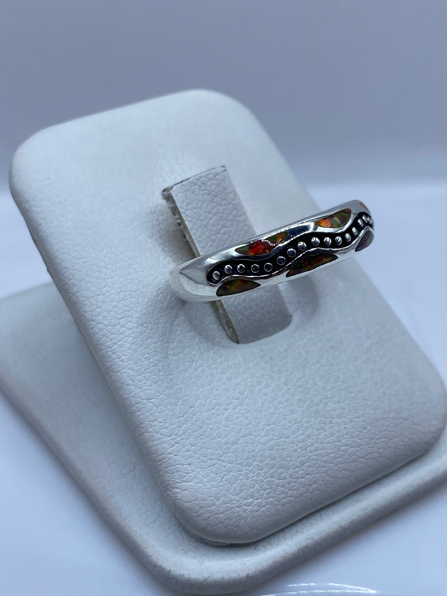 Detalle frontal del ópalo de fuego con tonos rojo, naranja, verde y ámbar en anillo de plata pura