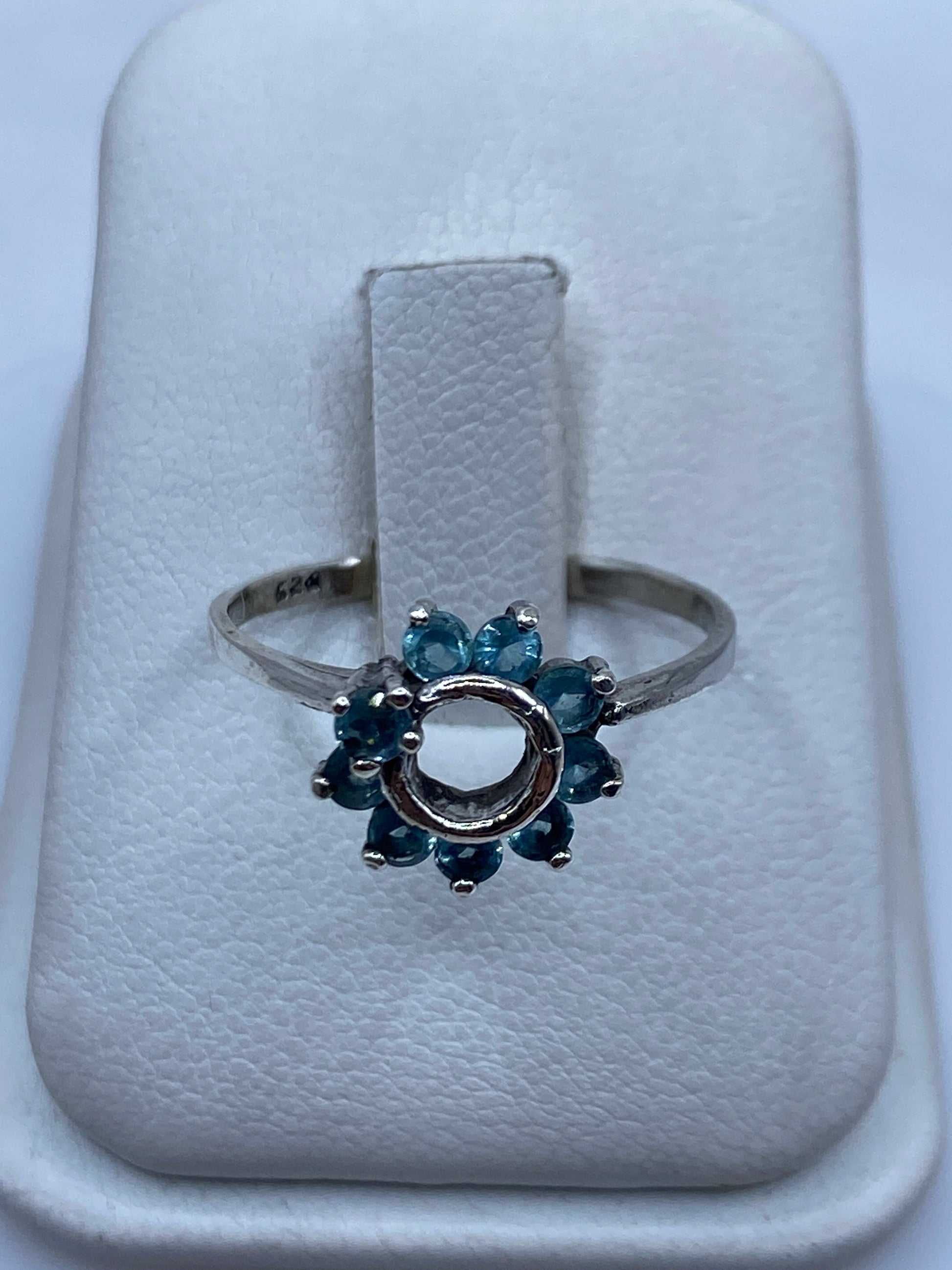Anillo solitario de plata con circonia azul cielo en la mano de una mujer