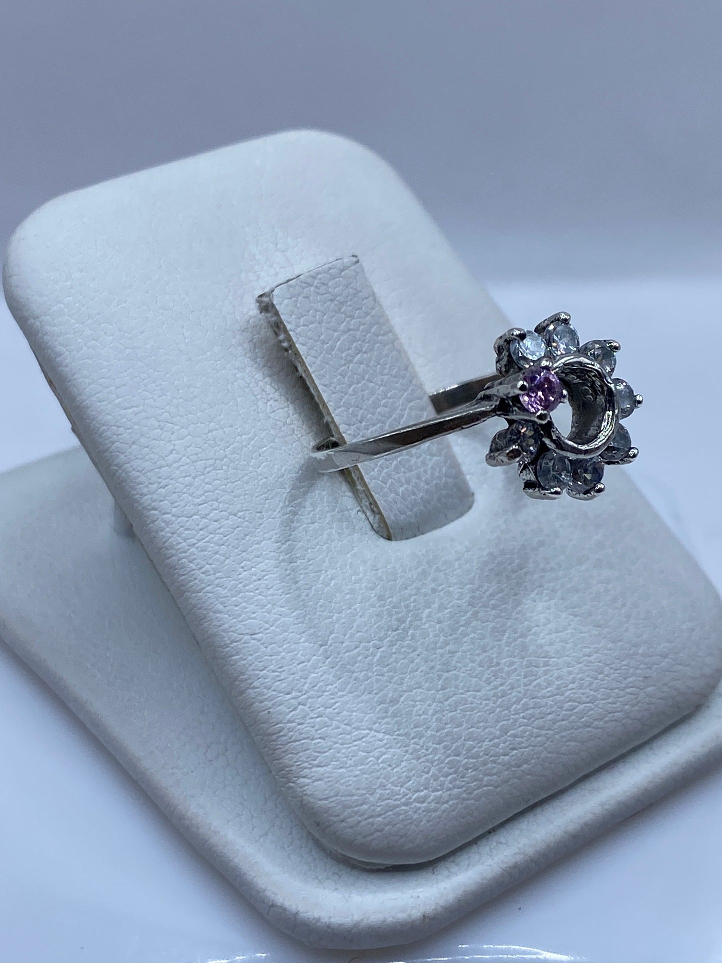 Vista frontal del anillo delgado con piedra blanca en mano de mujer