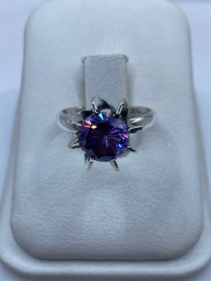 Anillo solitario de plata .925 con circonia morada facetada, visto desde arriba sobre cojín blanco