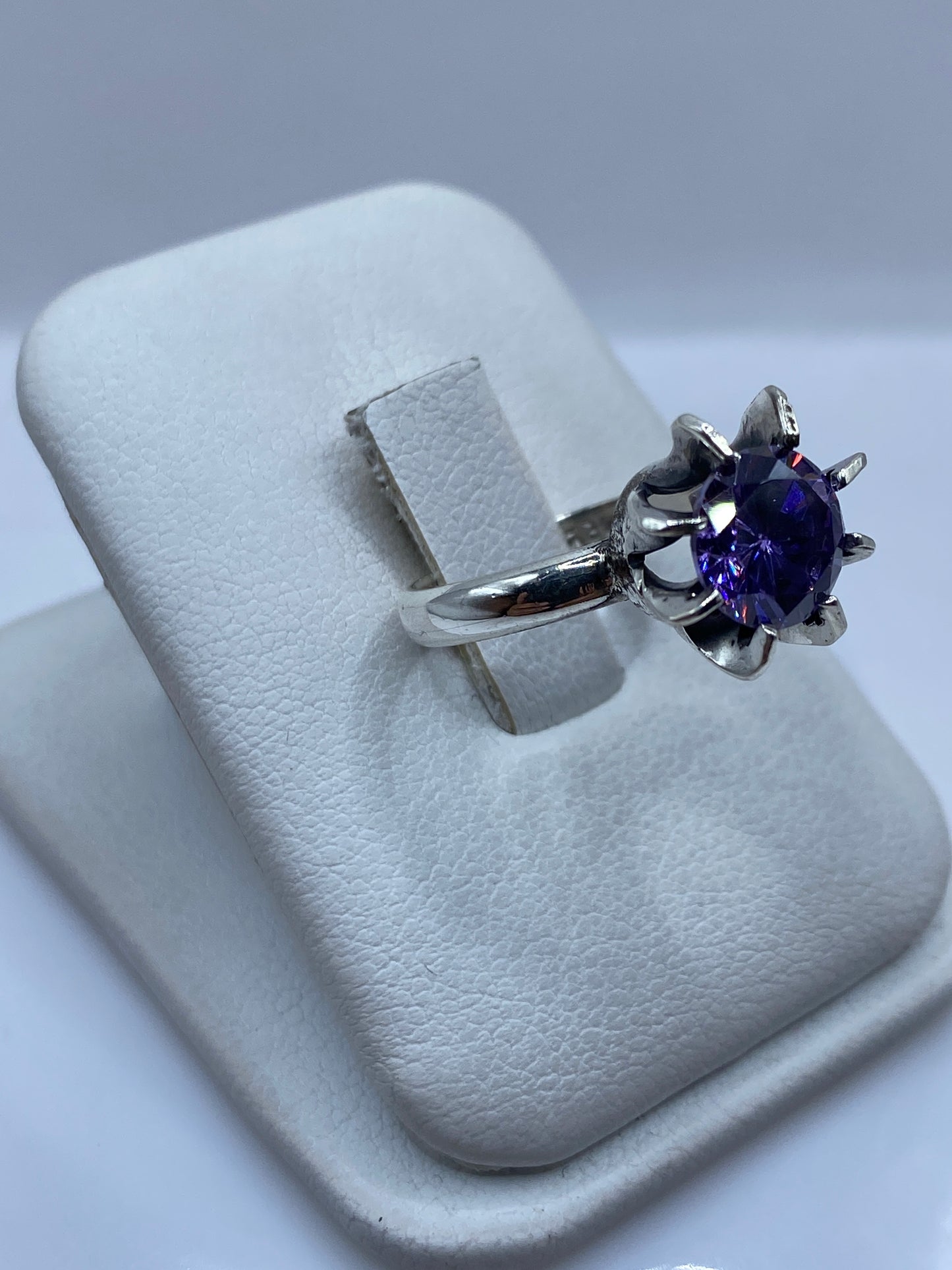 Detalle lateral del anillo morado en plata, mostrando el pulido espejo y el engaste a mano