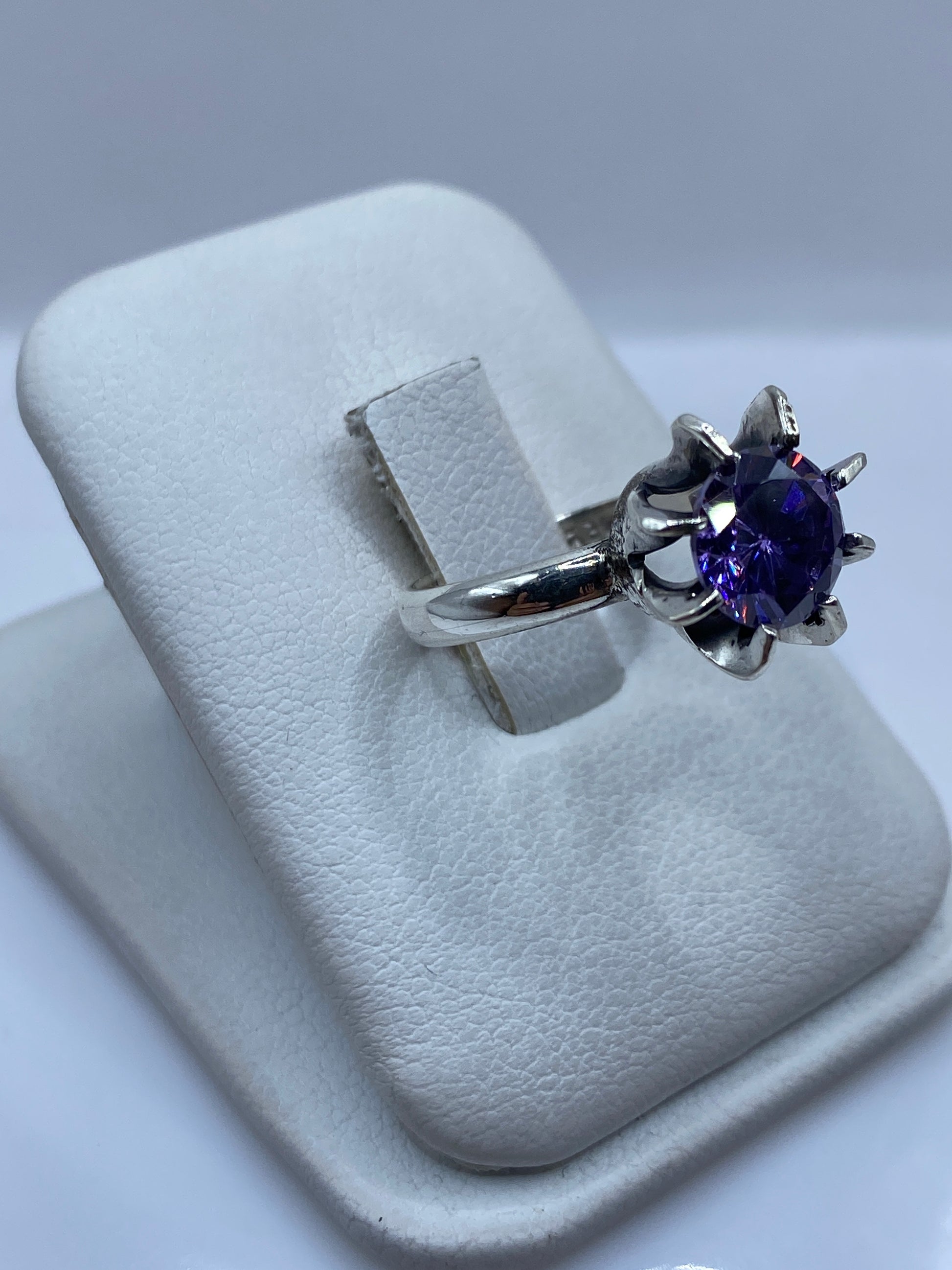 Detalle lateral del anillo morado en plata, mostrando el pulido espejo y el engaste a mano