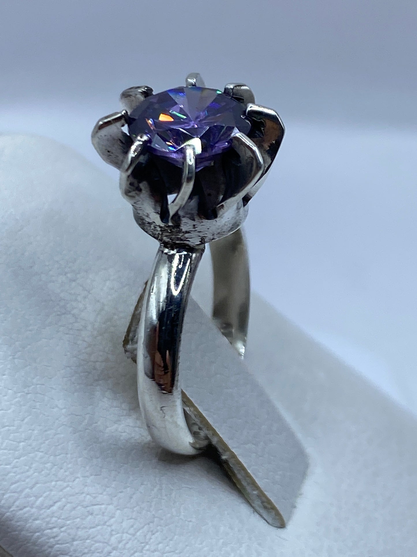 Anillo solitario morado en dedo de mujer, con luz natural realzando el brillo de la circonia