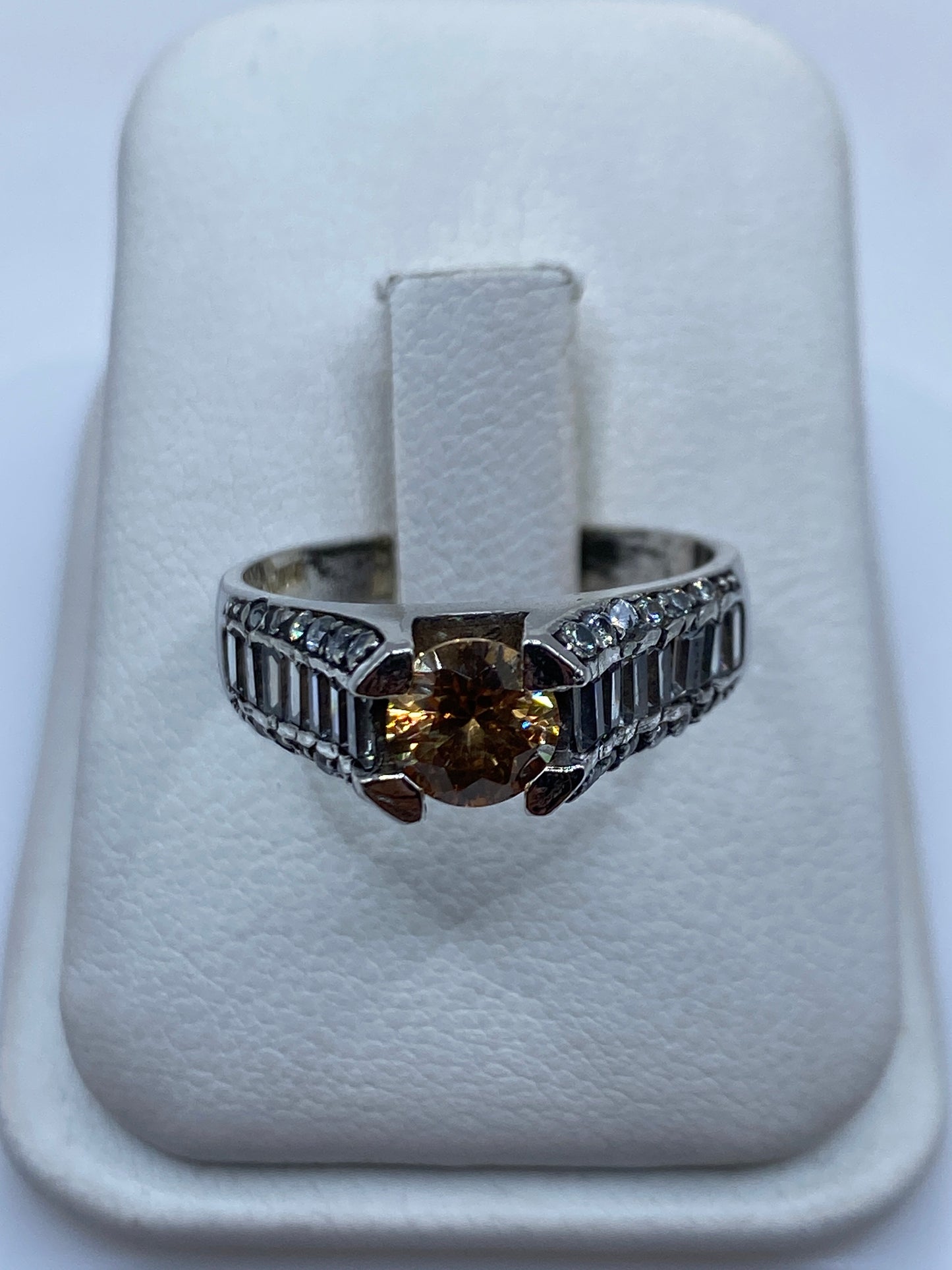 Anillo de plata solitario con circonia café en la mano de una mujer, mostrando el brillo cálido de la piedra