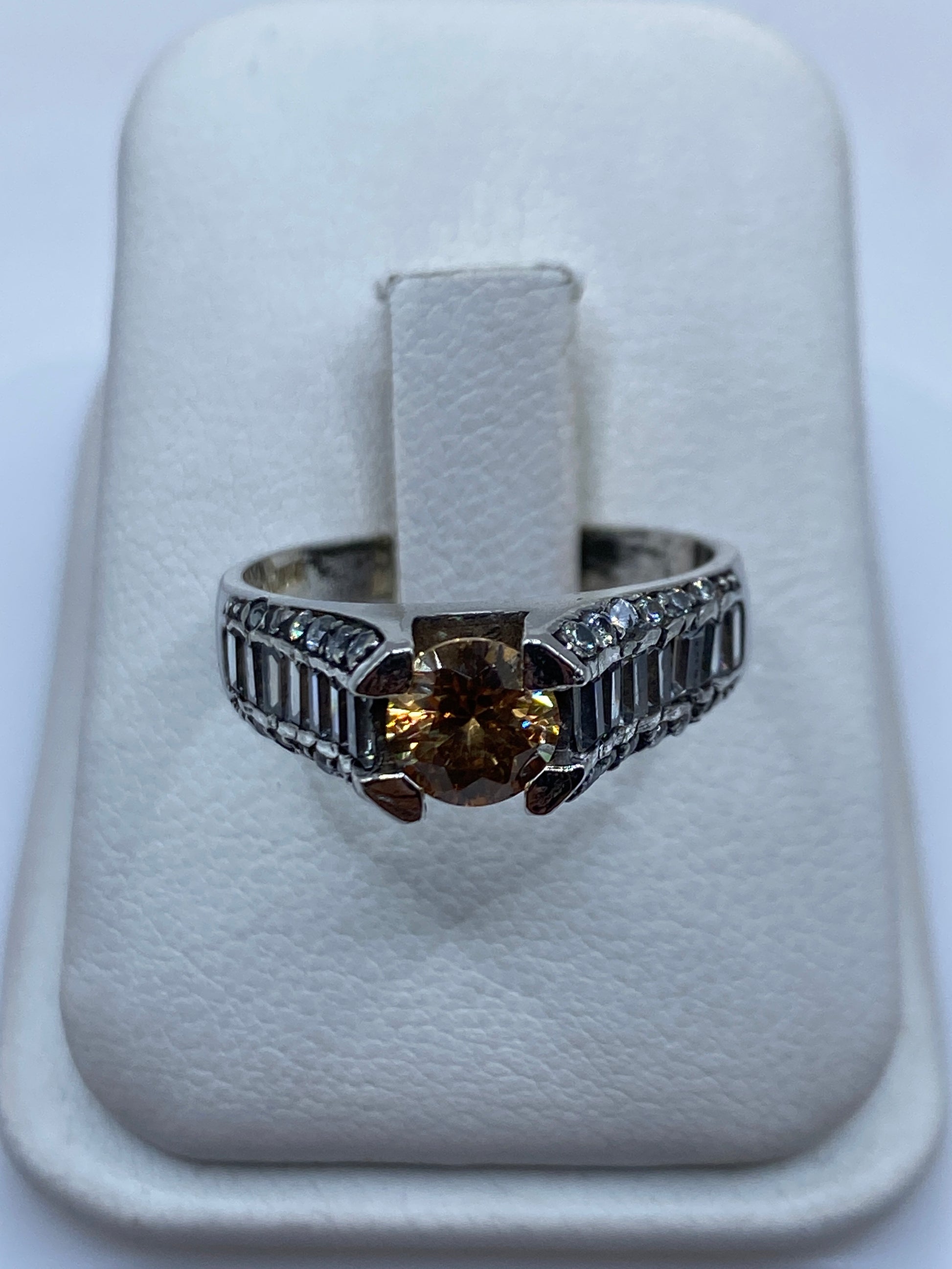Anillo de plata solitario con circonia café en la mano de una mujer, mostrando el brillo cálido de la piedra