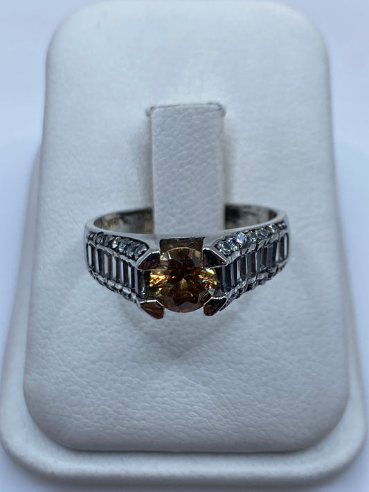 Anillo de plata solitario con circonia café en la mano de una mujer, mostrando el brillo cálido de la piedra