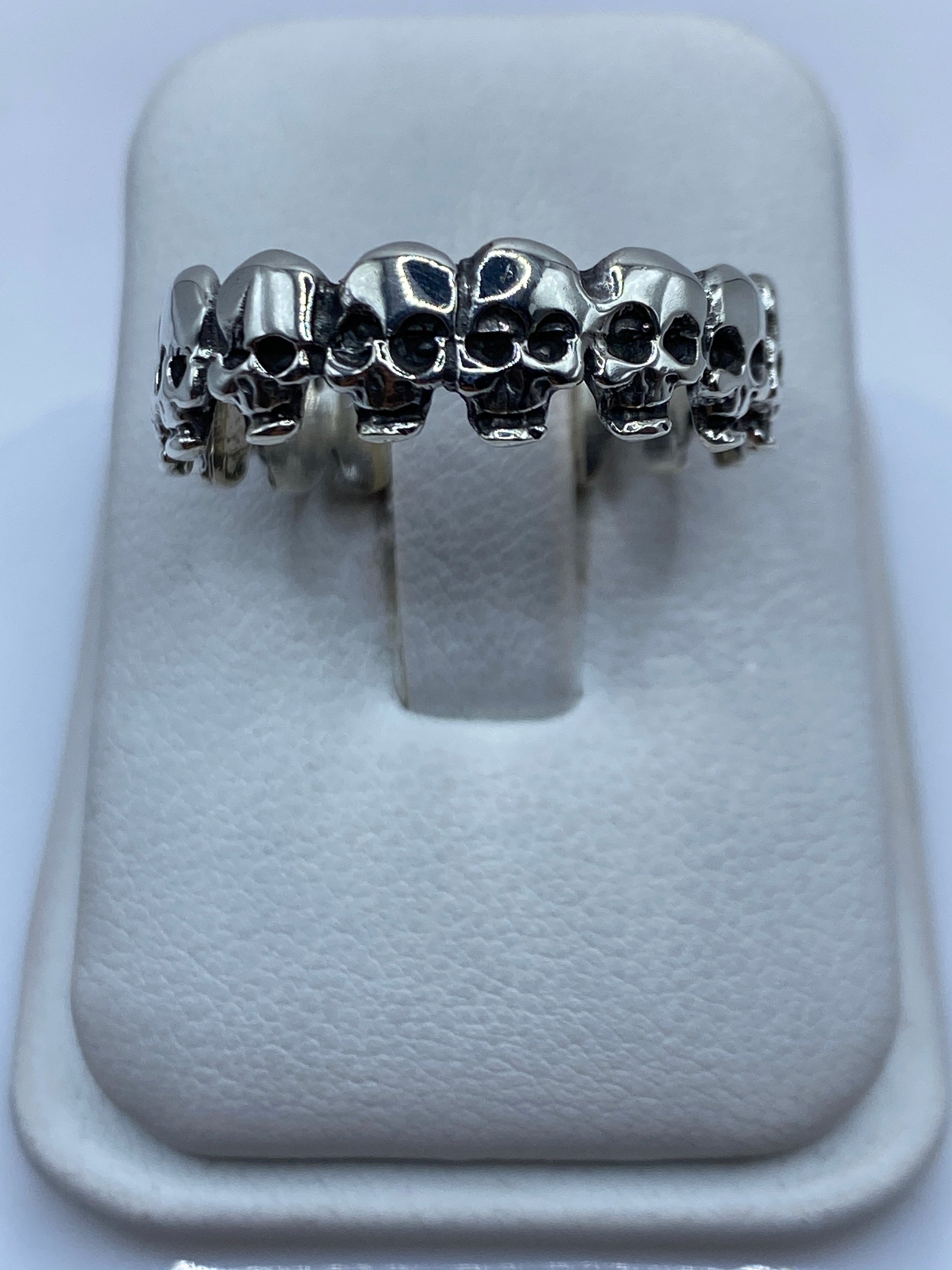 Anillo de plata con calaveras encadenadas visto desde arriba sobre fondo blanco