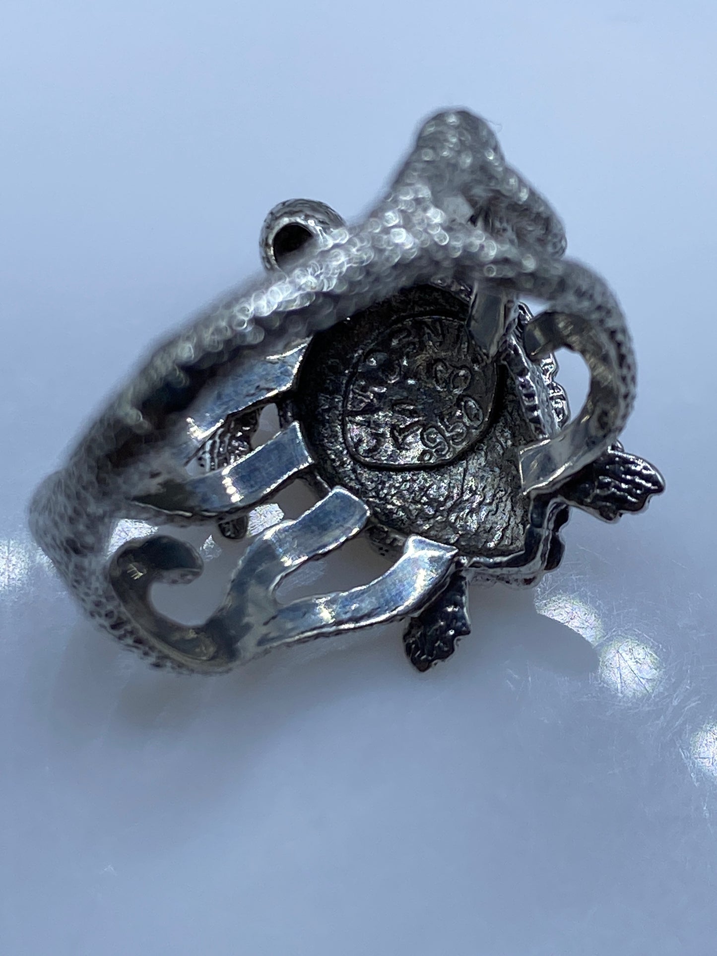 Anillo étnico sobre fondo gris mostrando el acabado pulido de la plata