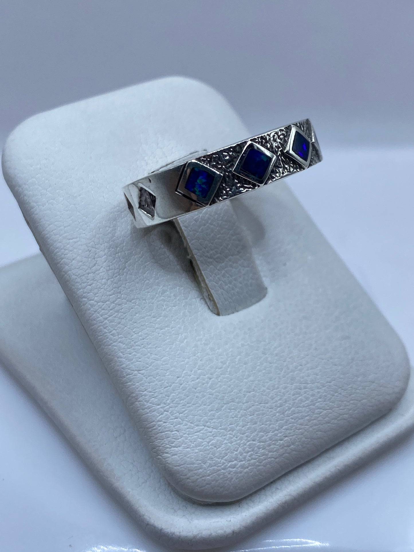 Anillo ópalo azul en la mano mostrando el juego de color natural de la piedra