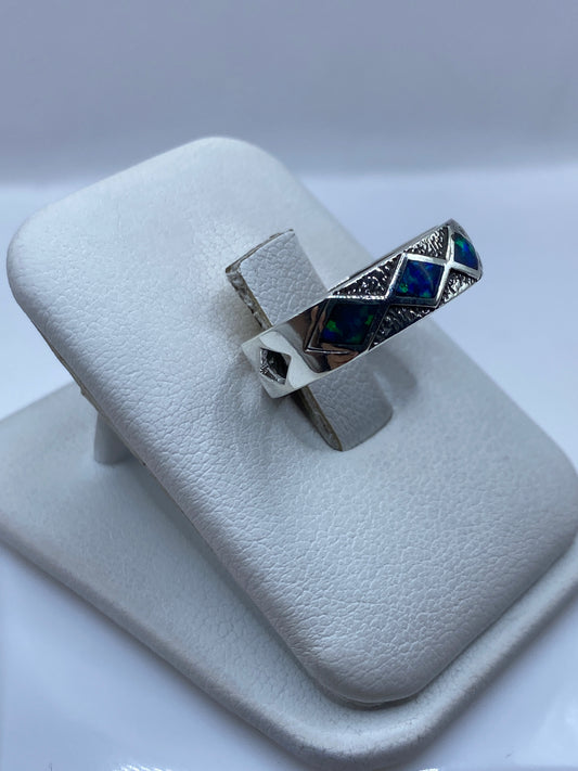 Anillo ópalo de fuego en plata sobre dedo mostrando el juego de colores azules y verdes