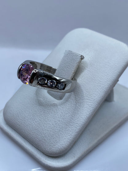 Vista frontal del anillo solitario con piedra rosa en la mano de una mujer
