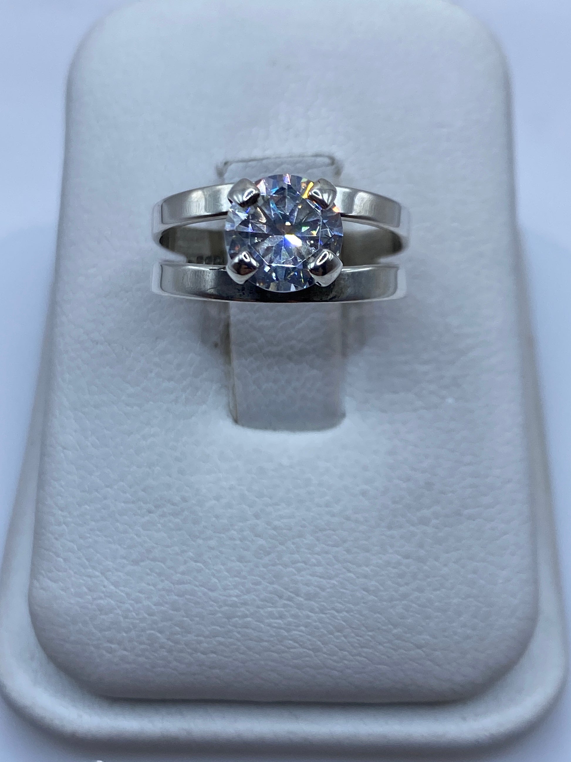 Anillo solitario de plata con circonia blanca brillante en la mano de una mujer