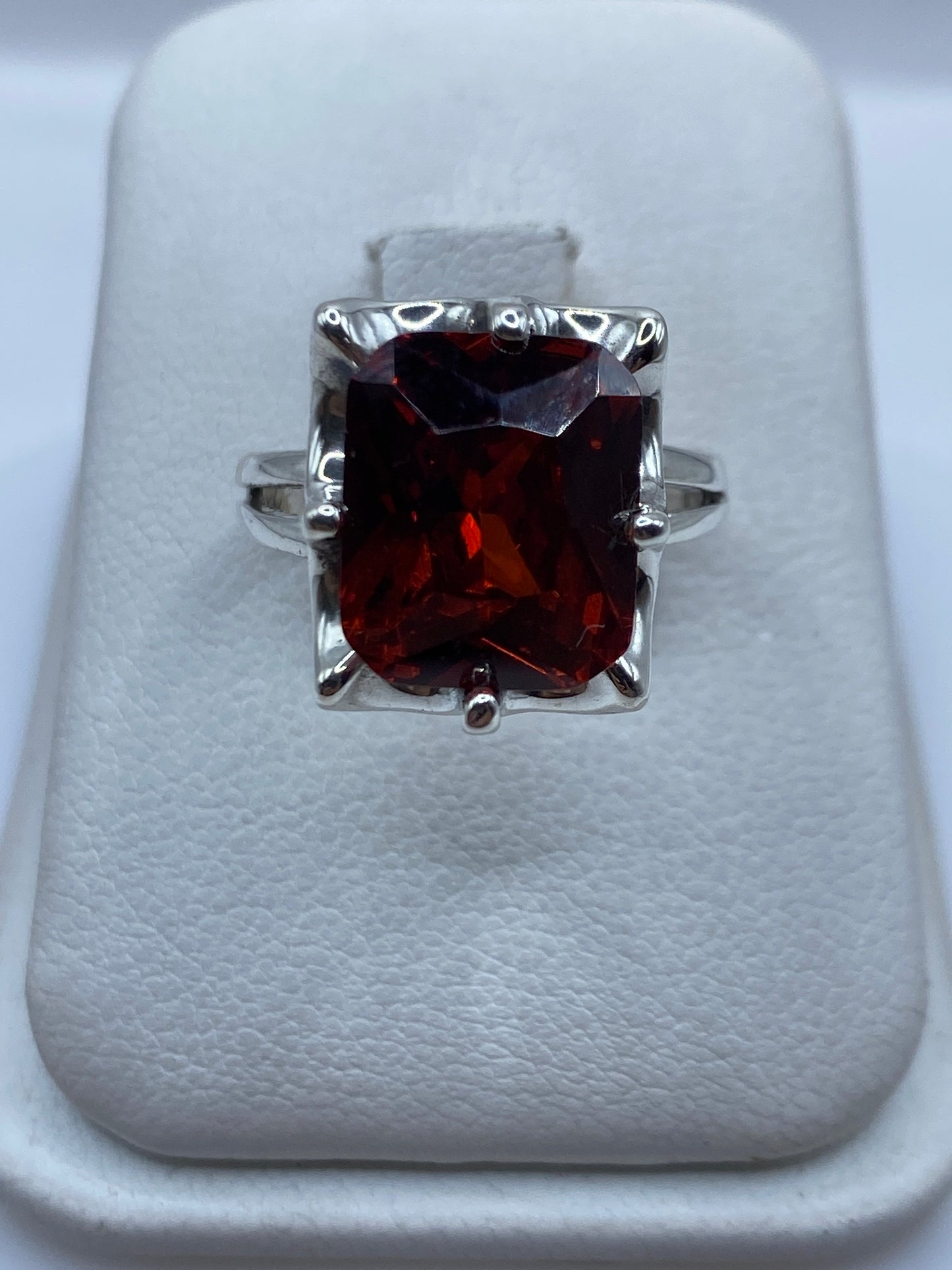 Anillo de plata solitario con circonia naranja en estuche blanco mostrando el brillo de la piedra