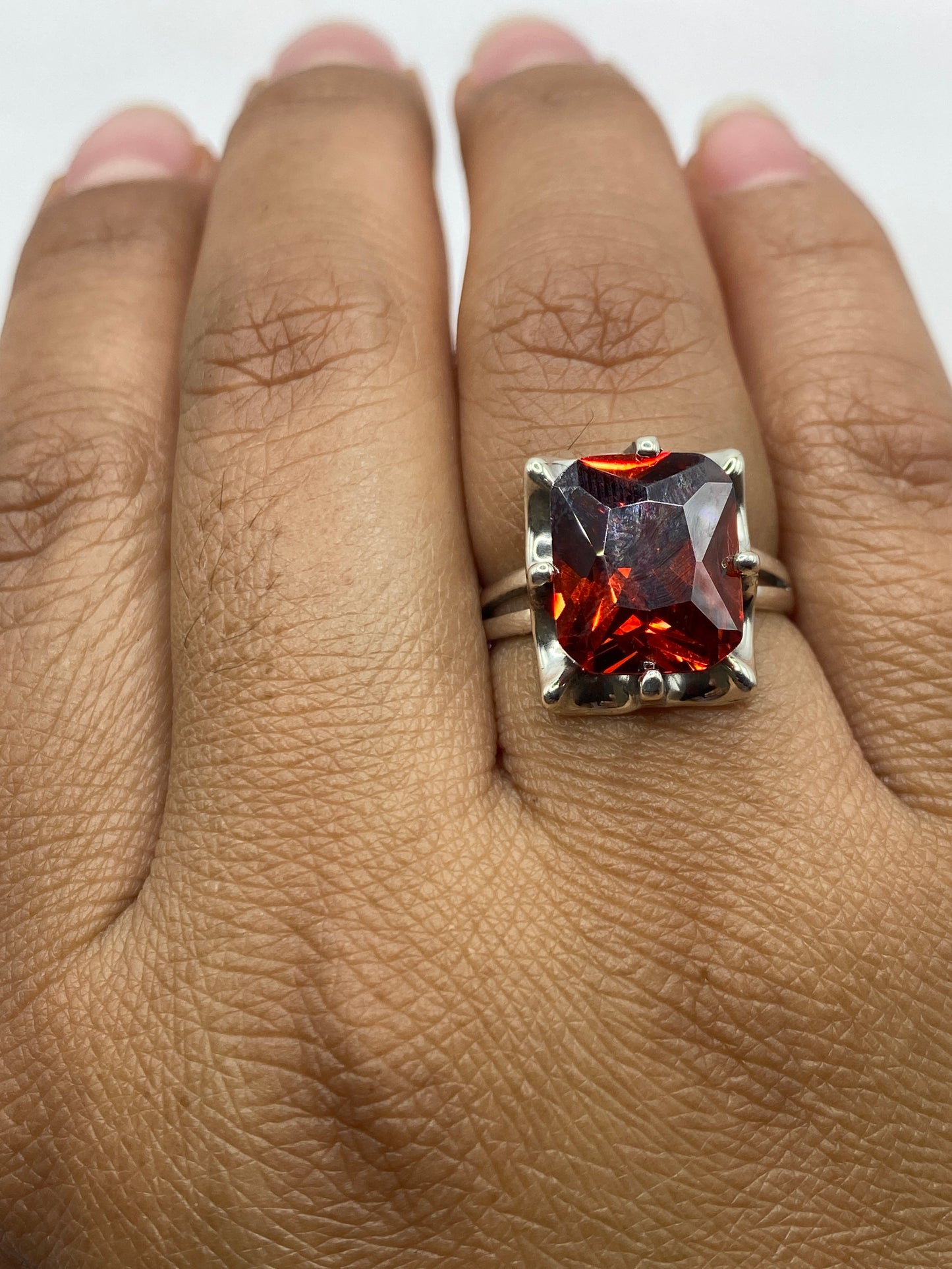 Anillo solitario en dedo mostrando el fuego naranja intenso de la circonia bajo luz natural
