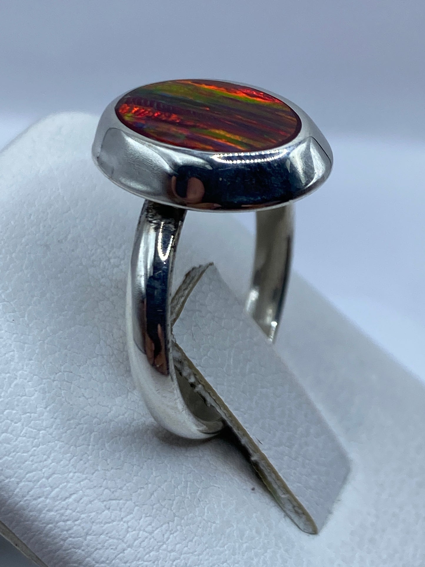 Anillo ópalo de fuego ajustable en la mano de una mujer con luz natural