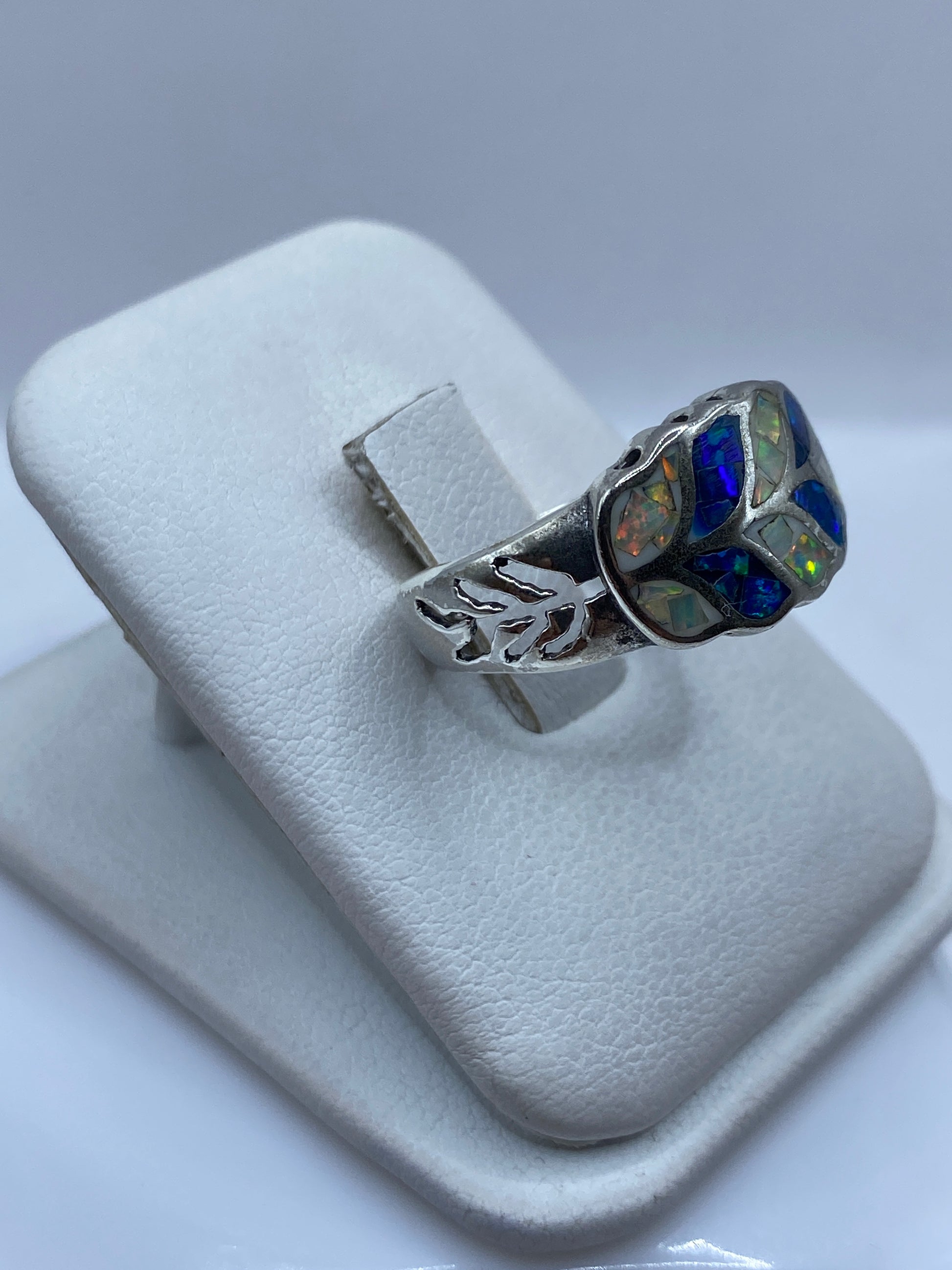 Anillo de plata pura engastado con ópalo de fuego en la mano de una mujer, viendo los destellos azules y verdes