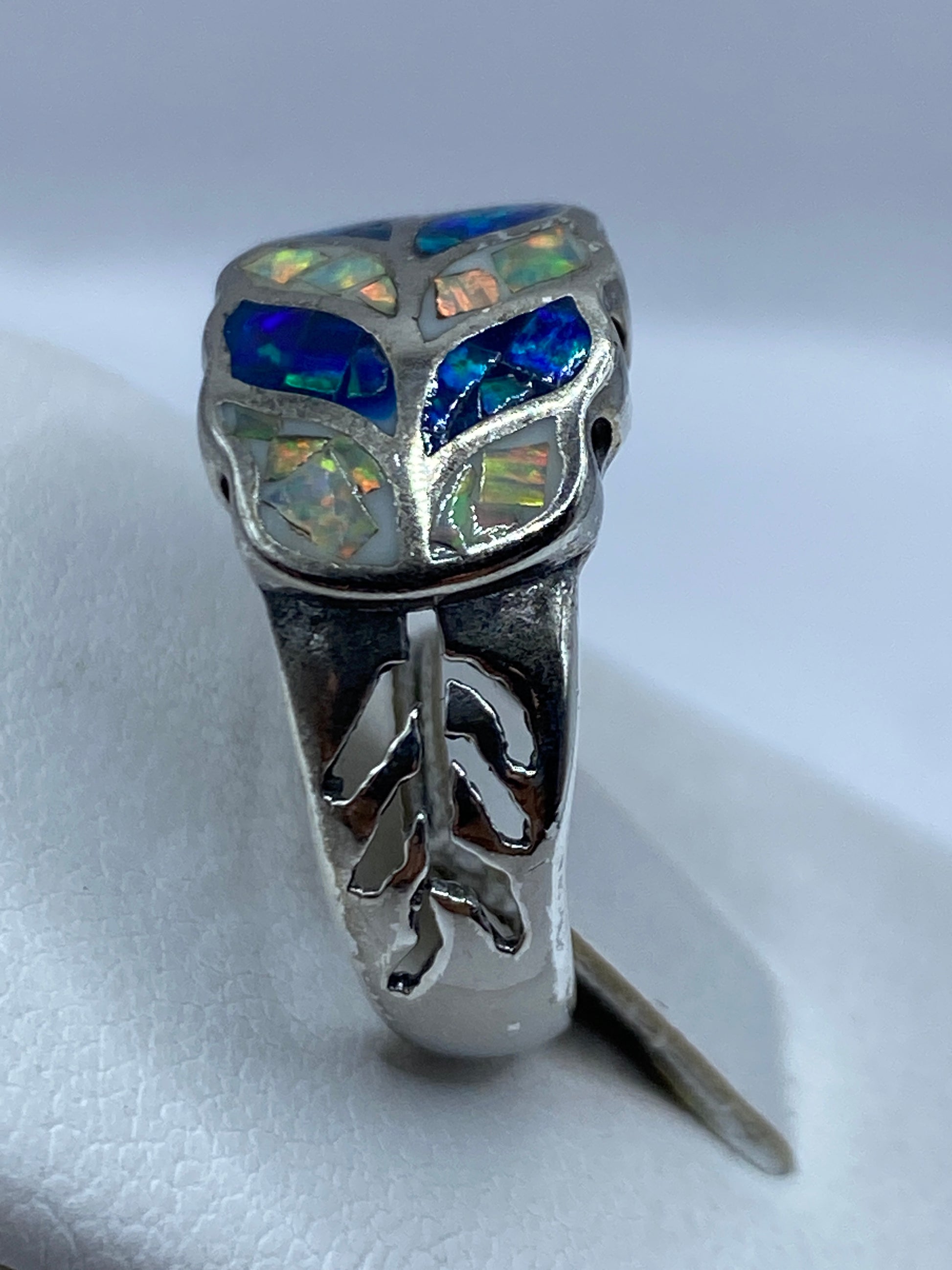 Vista lateral del anillo de ópalo multicolor mostrando la banda ornamentada de plata 950