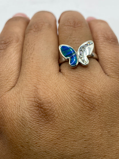 Ópalo de fuego azul en anillo mariposa, llevado en dedo de mujer, mostrando el brillo natural