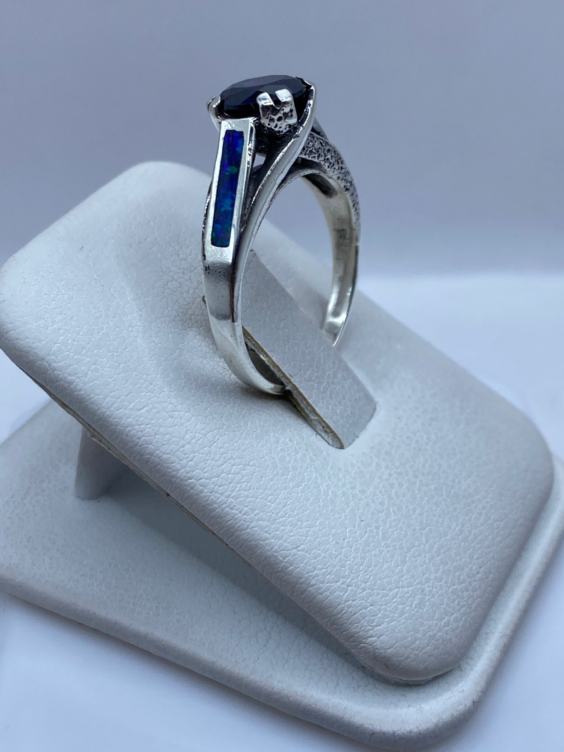 Vista frontal del anillo clásico con ópalo azul natural y banda texturada