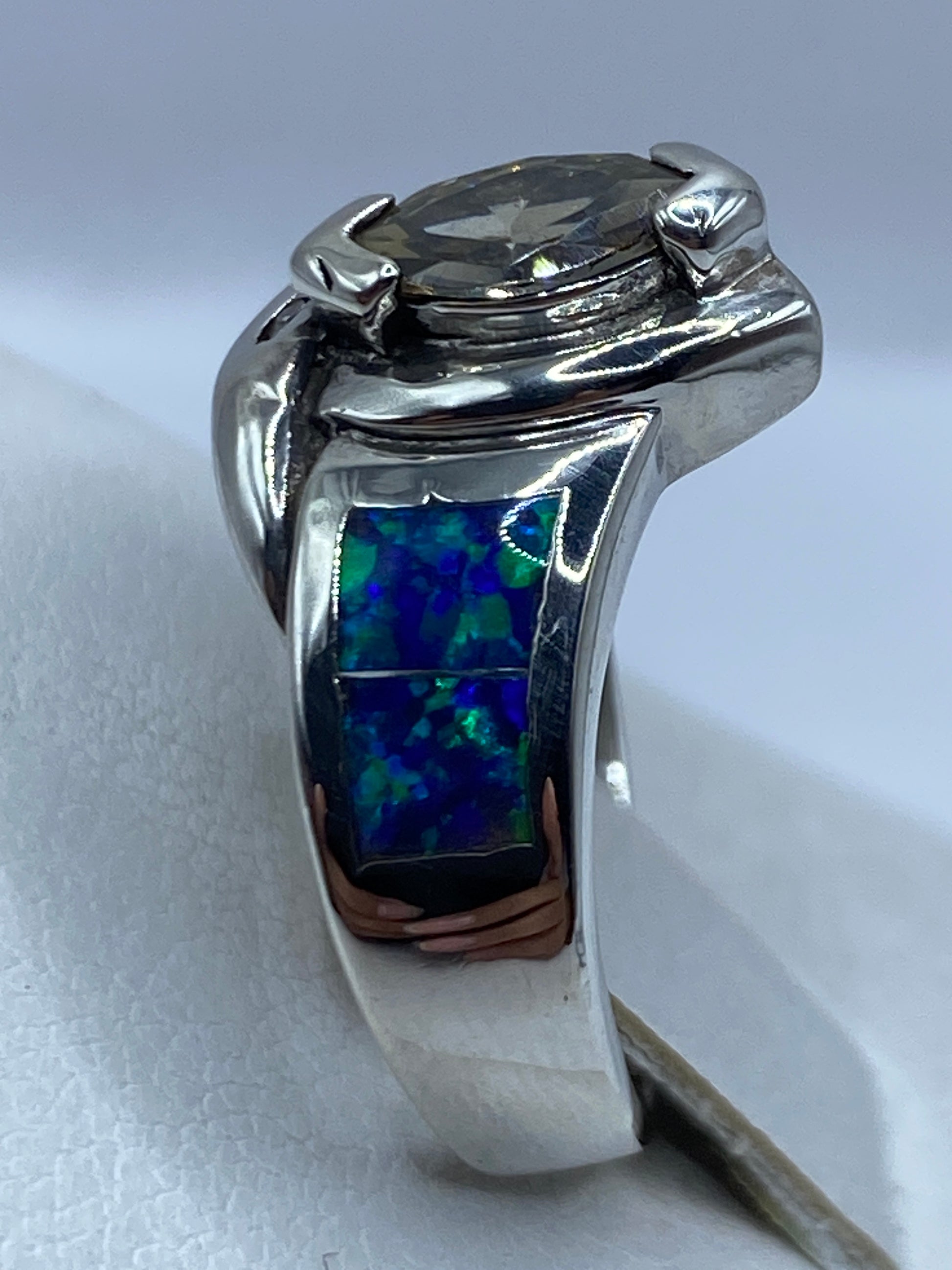 Anillo ópalo de fuego con detalles del juego de colores azul y verde, llevado en dedo