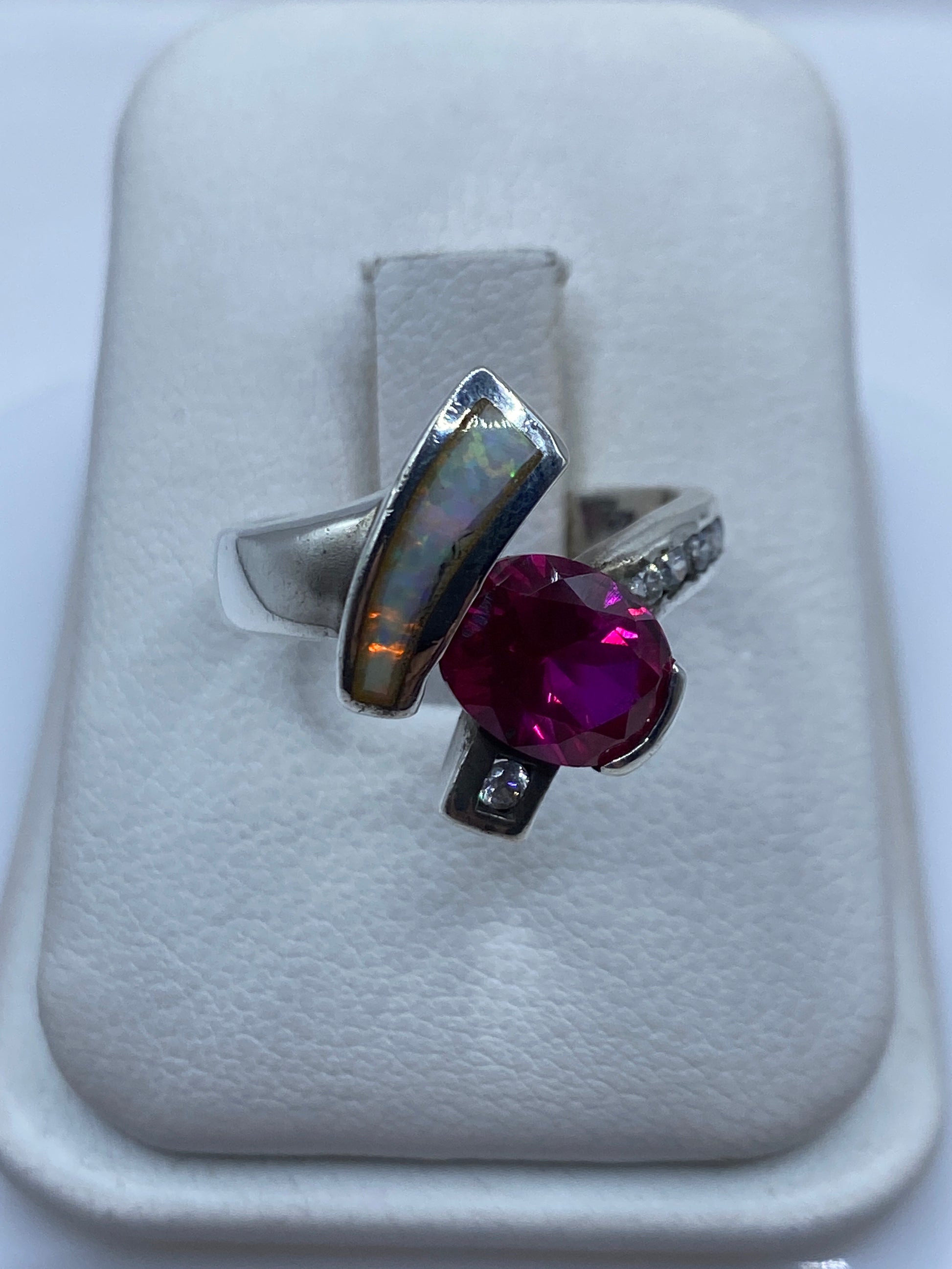Anillo de plata con ópalo de fuego mostrando destellos verdes y naranjas en caja de presentación