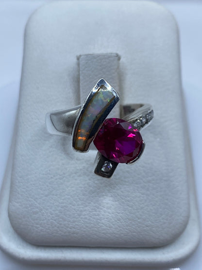 Anillo de plata con ópalo de fuego mostrando destellos verdes y naranjas en caja de presentación