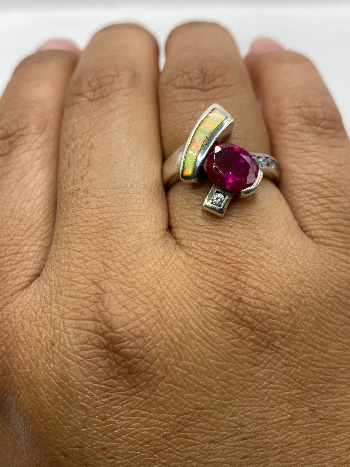 Anillo puesto en dedo mostrando el fuego único del ópalo bajo luz natural