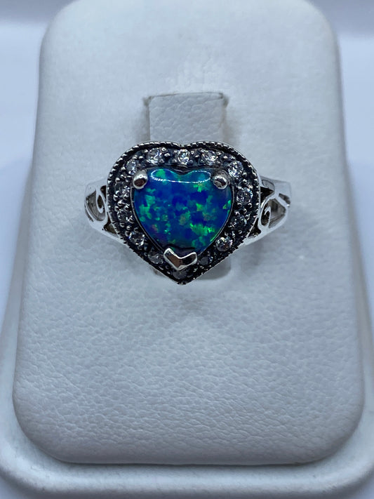 Anillo de plata corazón con ópalo de fuego azul y verde en dedo de mujer